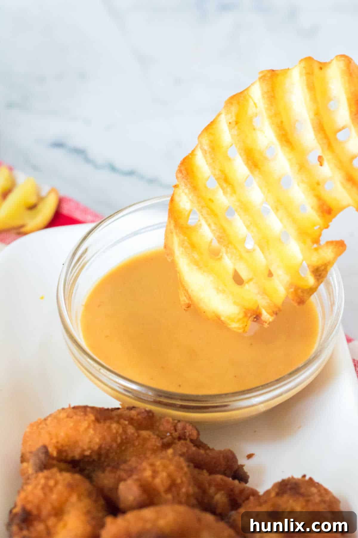 The Ultimate Homemade Chick-fil-A Nuggets 10 A crispy waffle fry is expertly dipped into a rich, creamy Chick-fil-A sauce, highlighting the perfect pairing.
