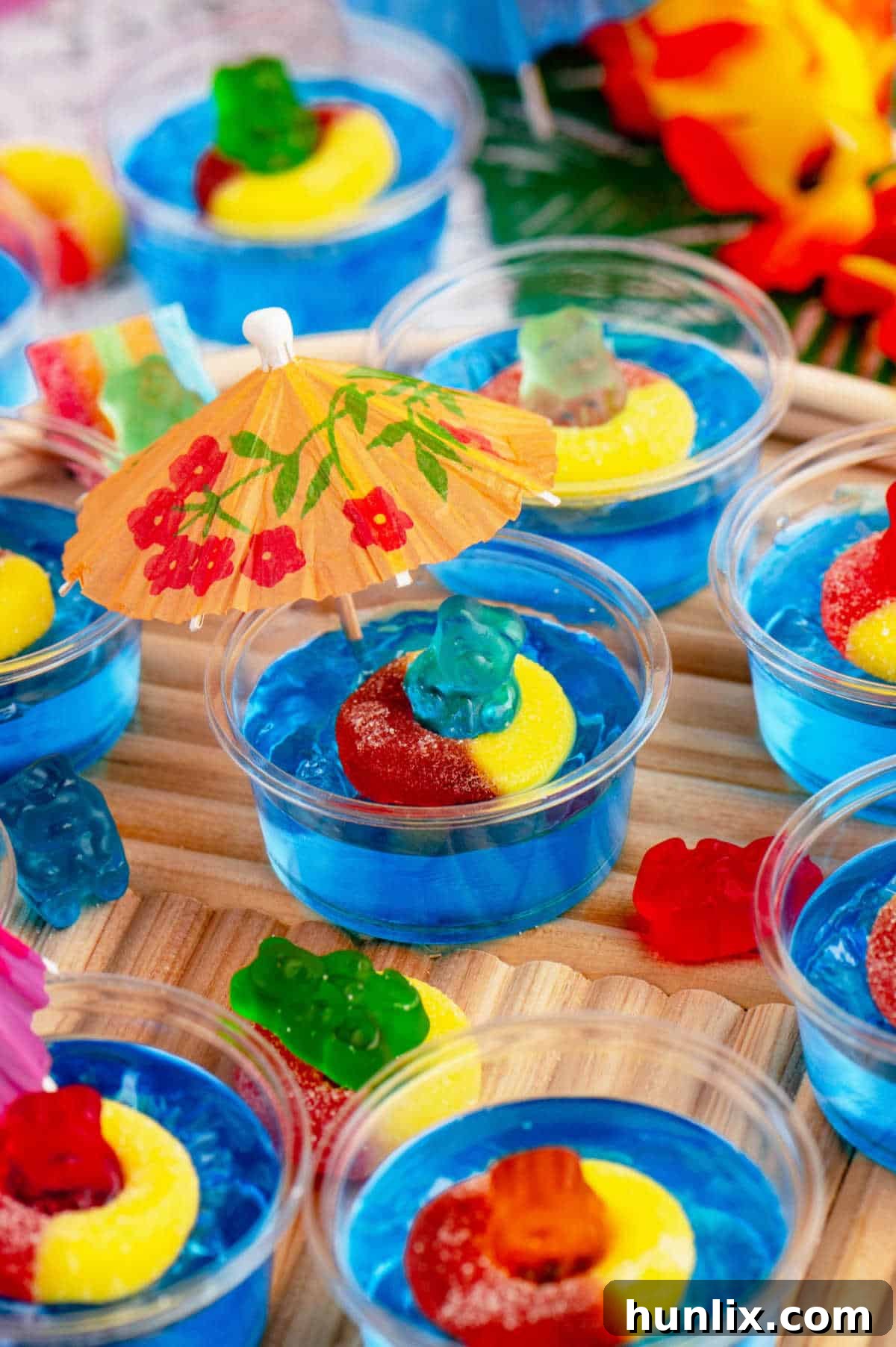 A close-up of a decorated Pool Party Jello Shot, showing the gummy bear floatie and blue jello, ready to be enjoyed.