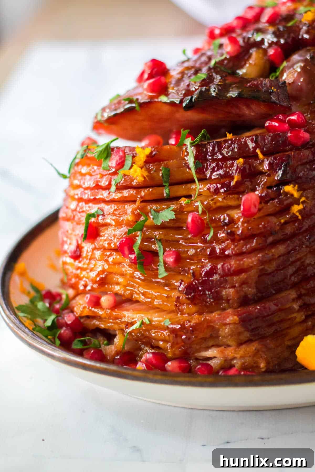 Christmas Glazed Ham 7 A festive platter of glazed Christmas ham, garnished with orange slices, pomegranate, and rosemary, ready to be served.