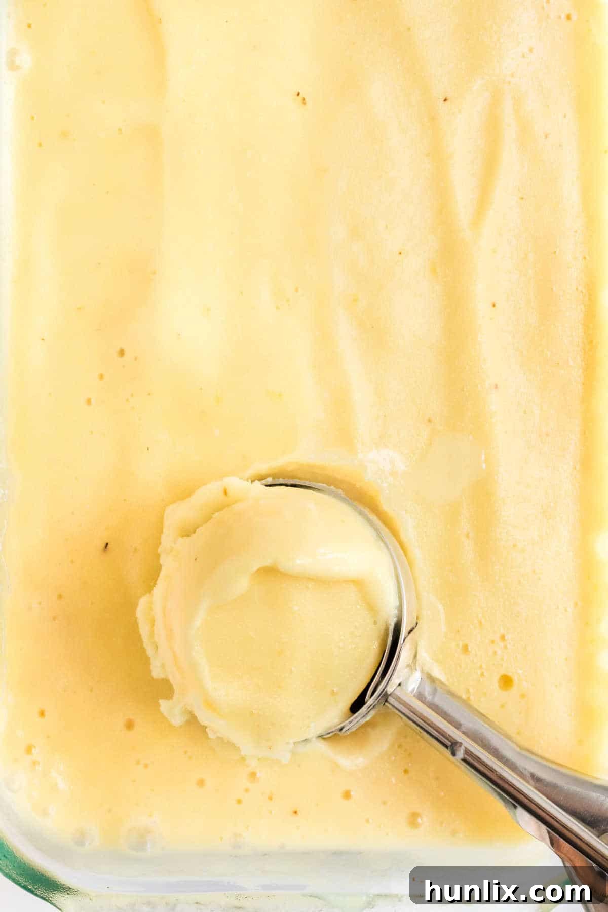 Pineapple ice cream with a scoop in it.