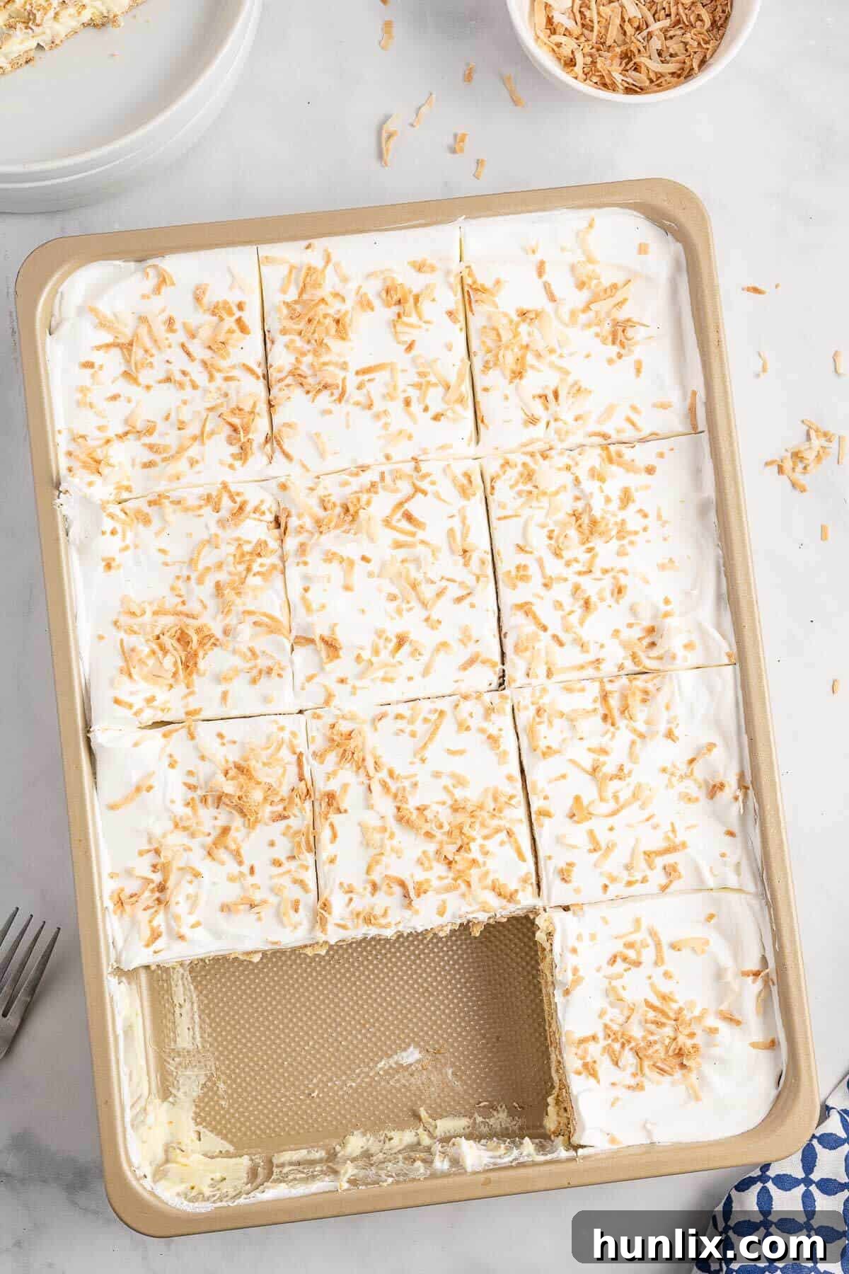 Creamy Coconut Chill Cake 2 A pan of coconut icebox cake cut into squares with two pieces missing.