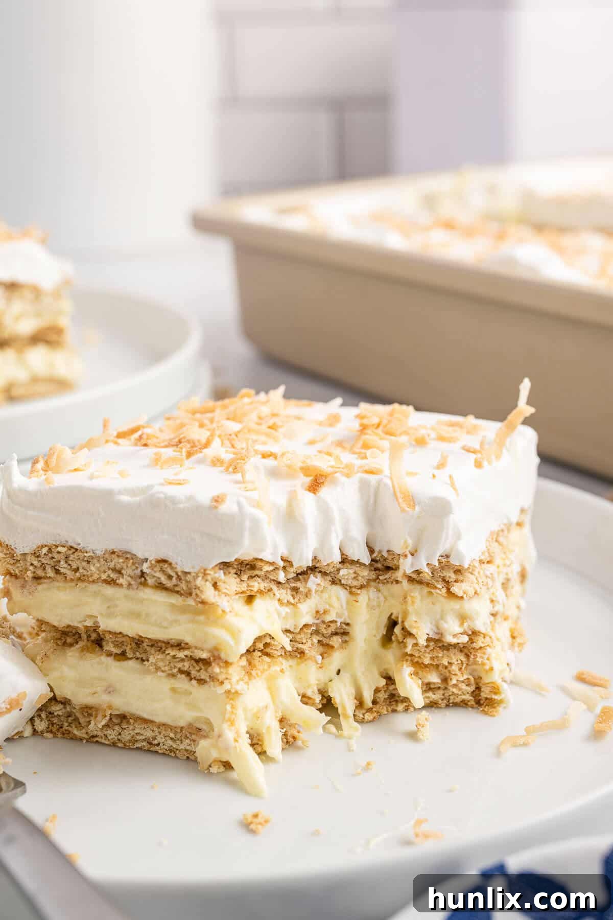 Creamy Coconut Chill Cake 12 A piece of cake on a plate with a bite taken out of it.