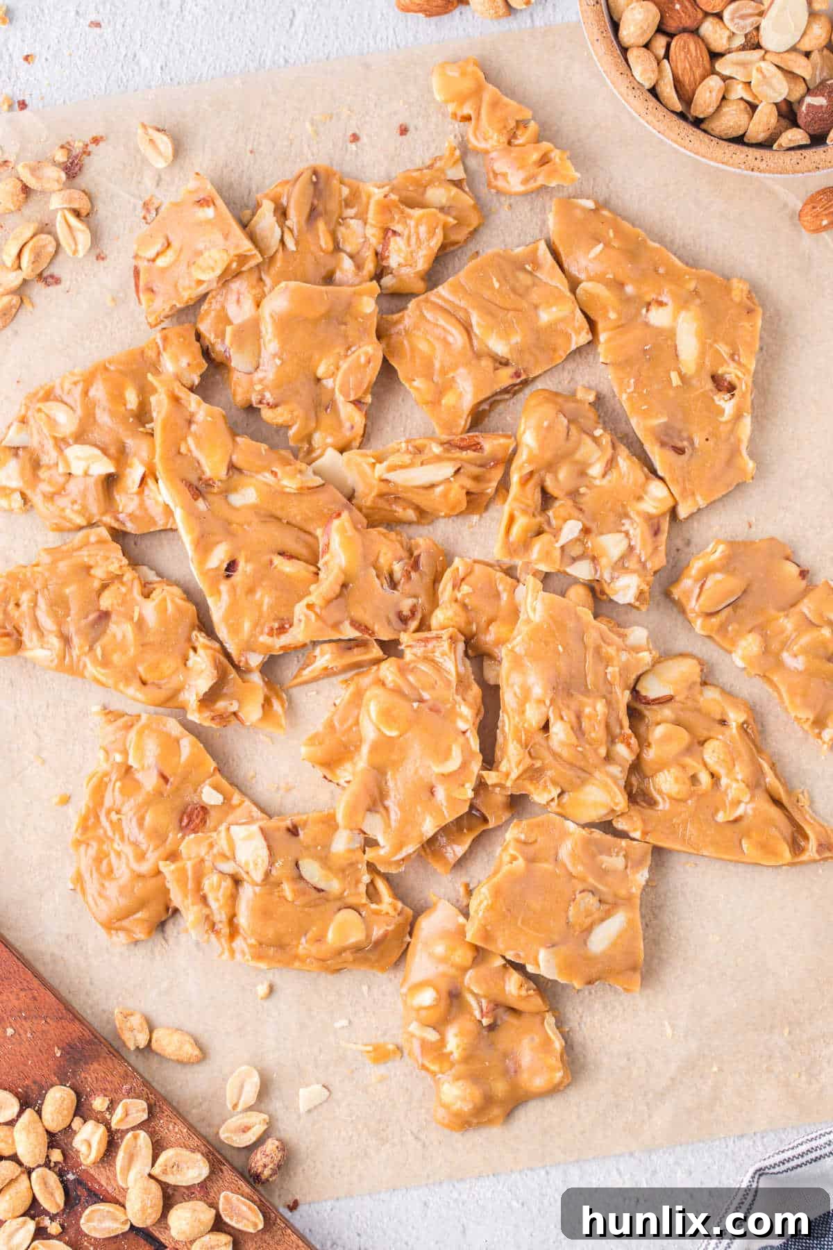 Nutty Caramel Crunch 2 Caramel nut brittle on a piece of brown parchment paper.