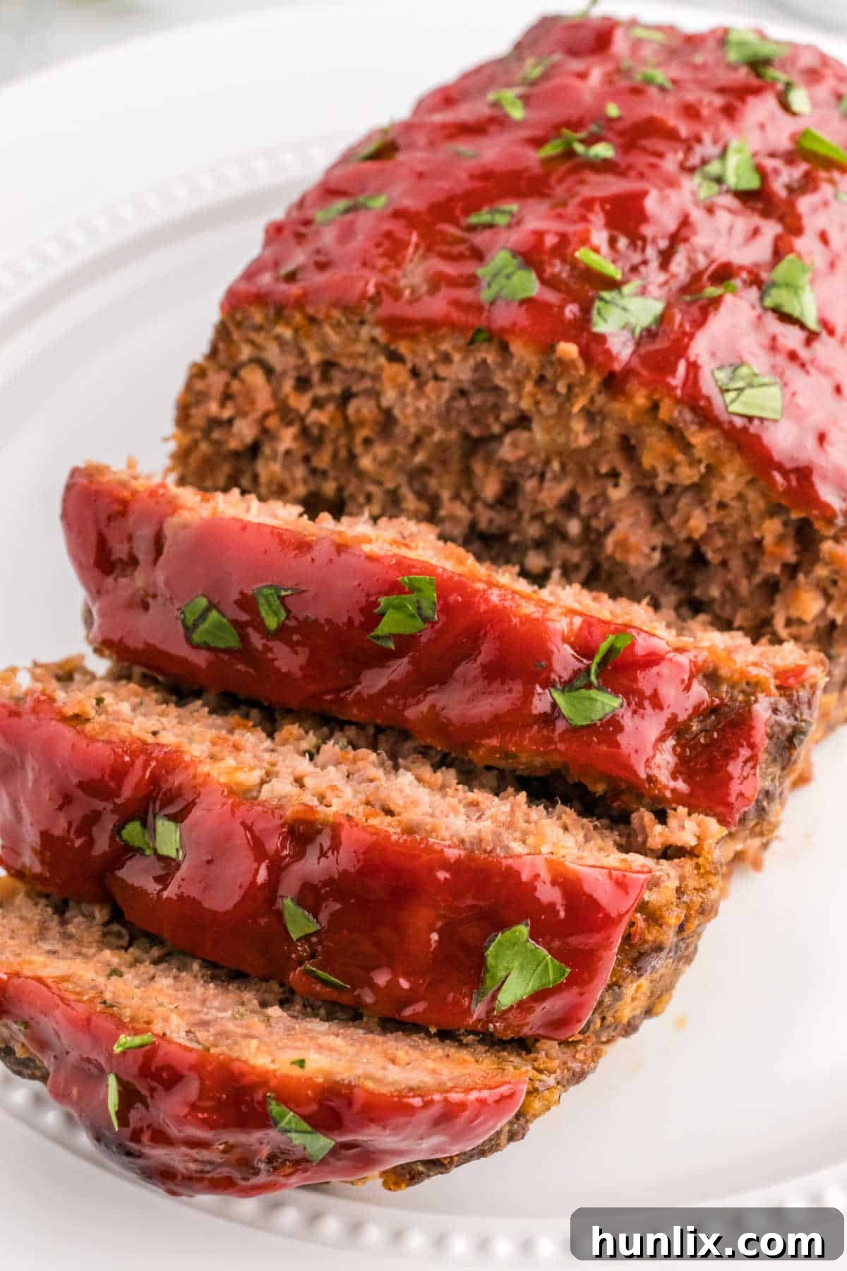 A freshly baked meatloaf, sliced at one end, on a serving platter, showing its moist interior and delicious crust.