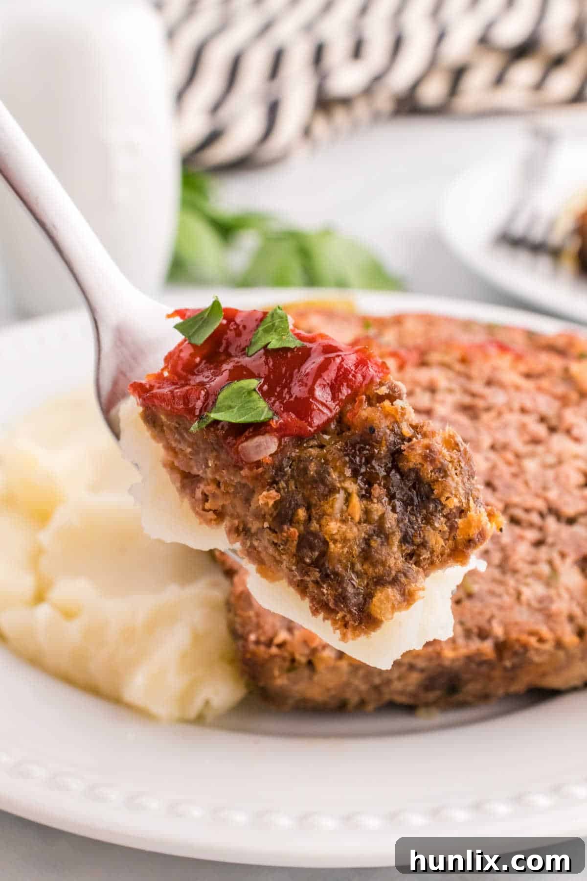 A slice of meatloaf on a fork, showing its tender texture and the delicious glaze.