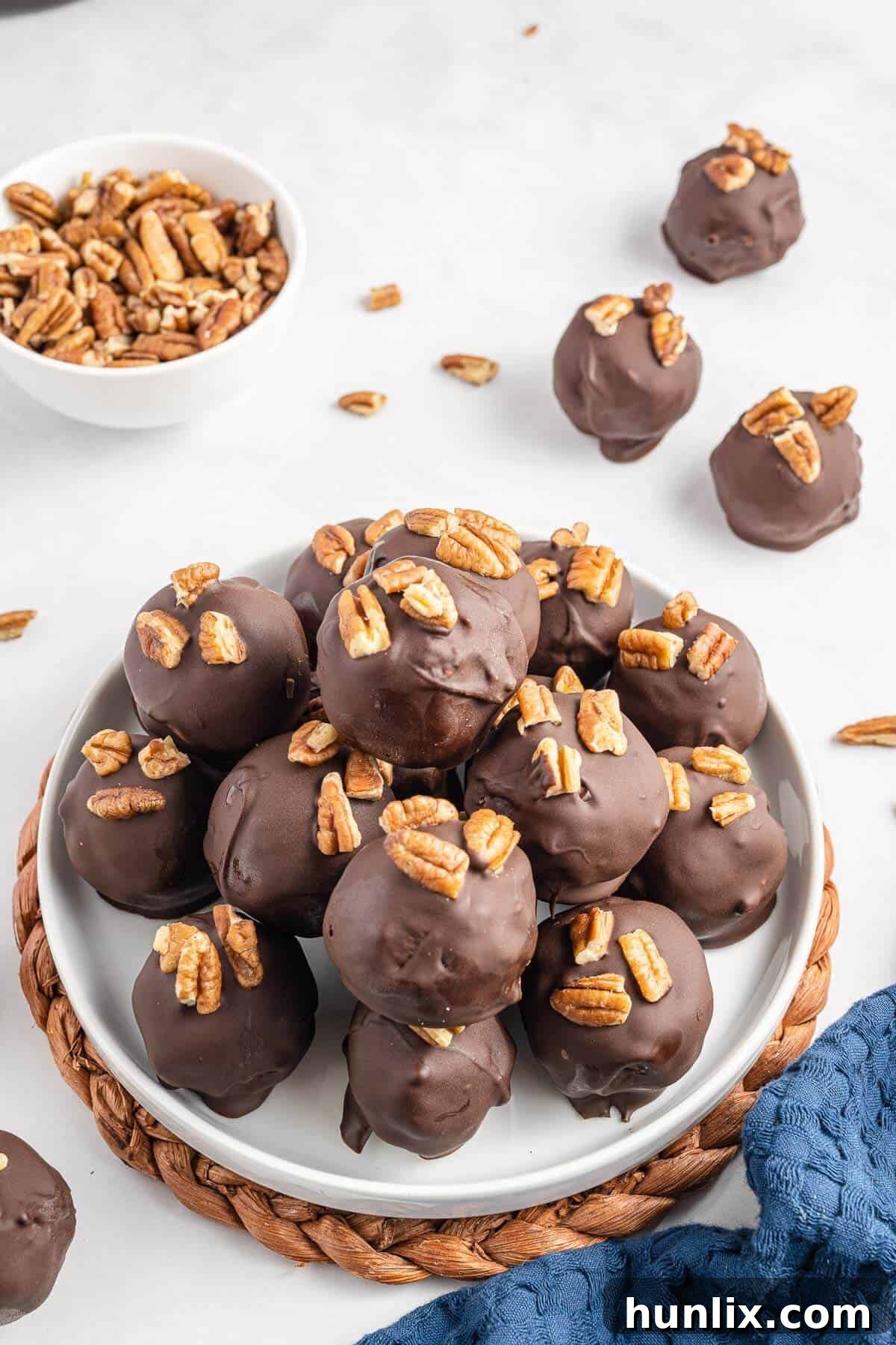 Pecan Pie Truffles 2 Pecan pie balls piled artfully on a pristine white plate, showcasing their inviting texture and chocolate coating.