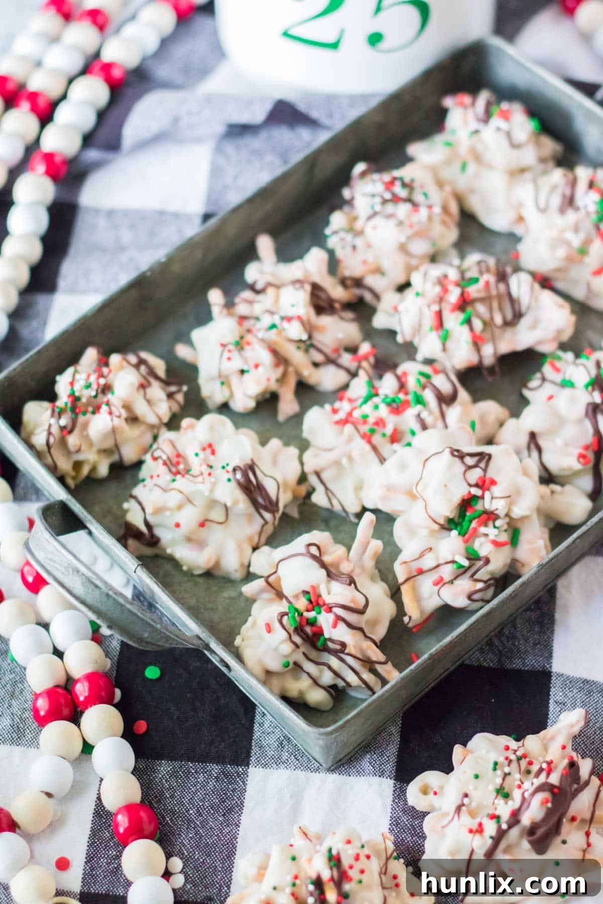 A metal tray filled with freshly made peppermint crockpot candy clusters, highlighting their appealing texture and festive sprinkles.