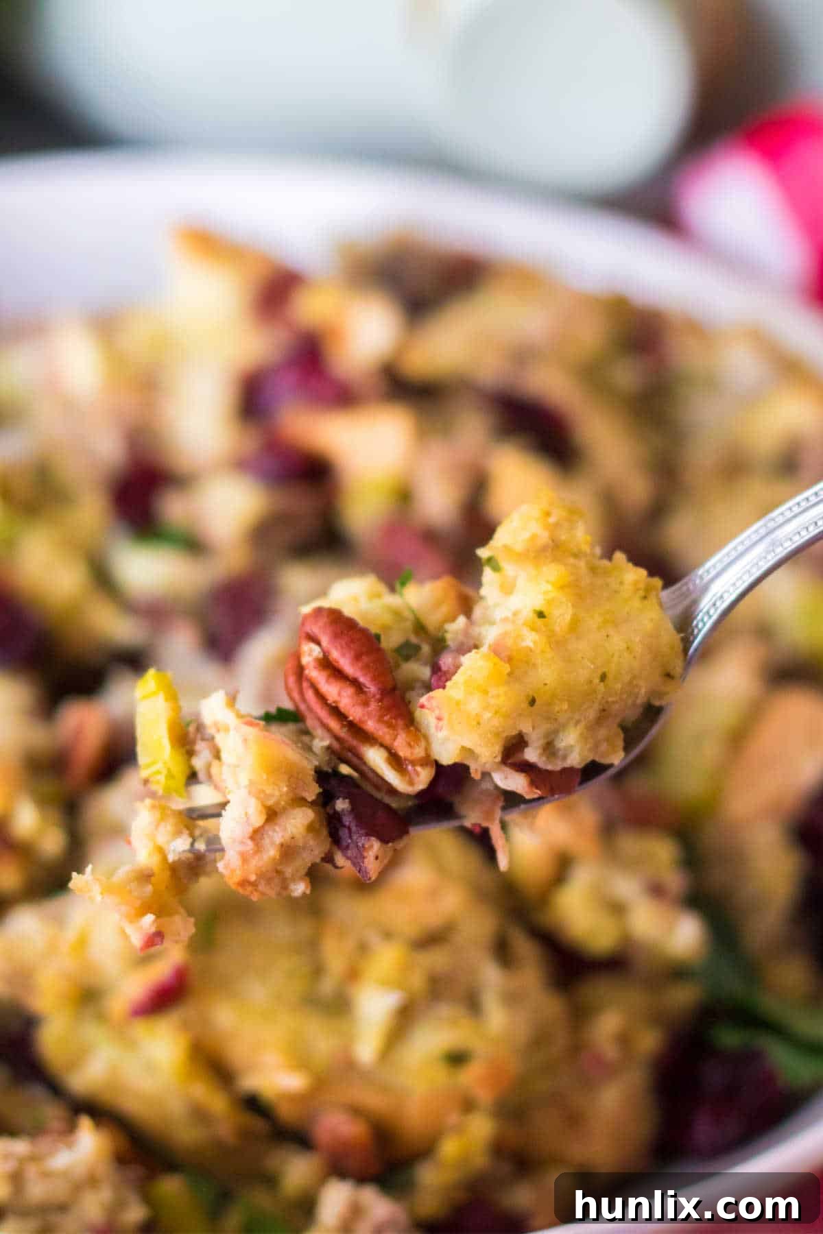 Effortless Slow Cooker Cranberry Pecan Stuffing 9 A fork lifting a piece of cranberry pecan stuffing, showcasing its rich texture and visible ingredients like cranberries and pecans.