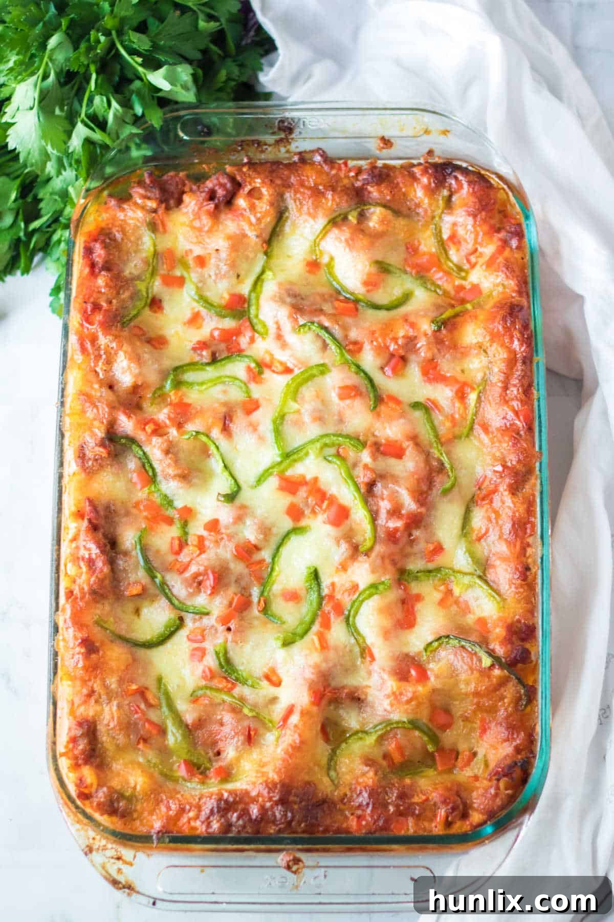 Festive Lasagna Delight 2 Christmas lasagna in a lasagna pan, ready to be served. Layers of pasta, sauce, sausage, and cheese are visible, garnished with red and green peppers.