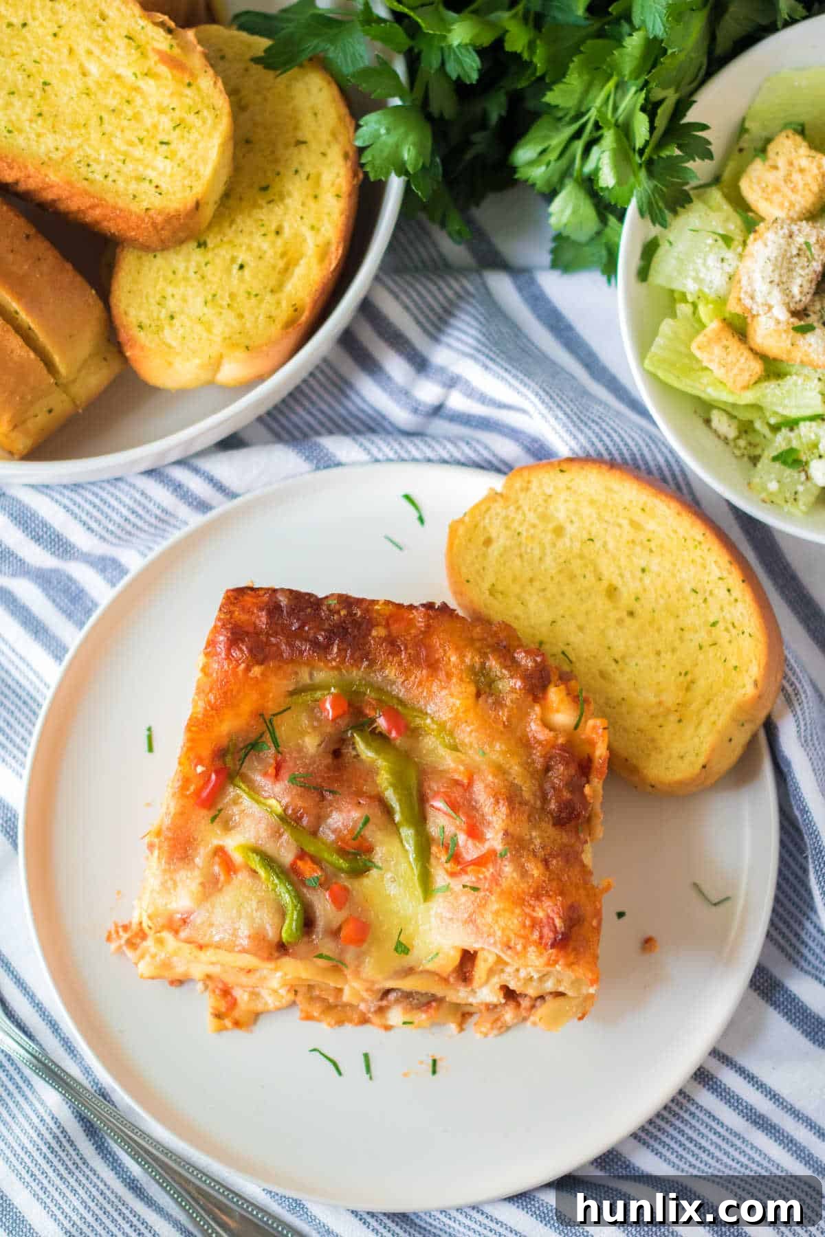 Festive Lasagna Delight 10 A slice of Christmas lasagna on a plate with garlic toast, showing the rich, cheesy layers.