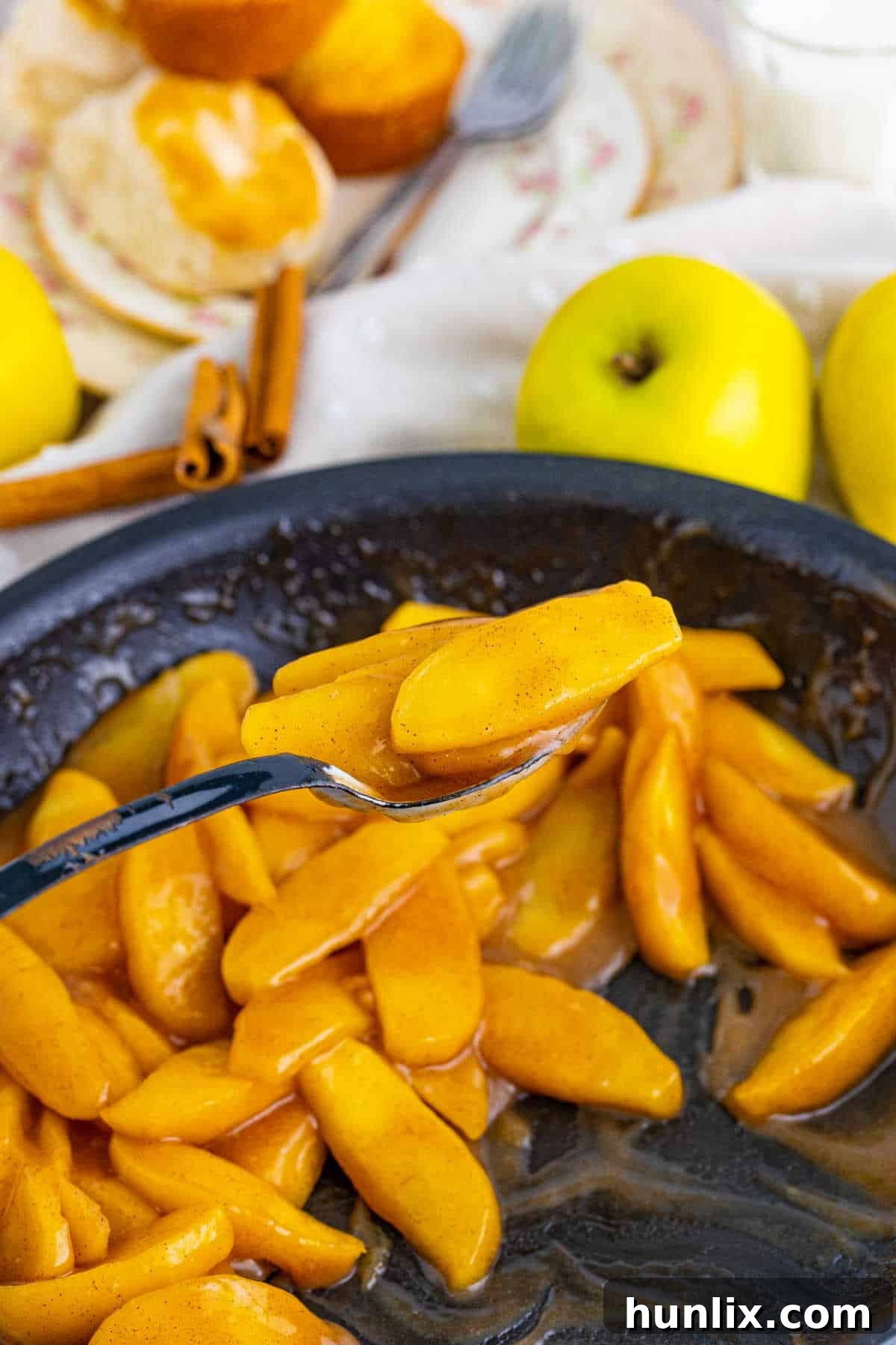 Fried apples in a skillet with a serving spoon, ready to be enjoyed.