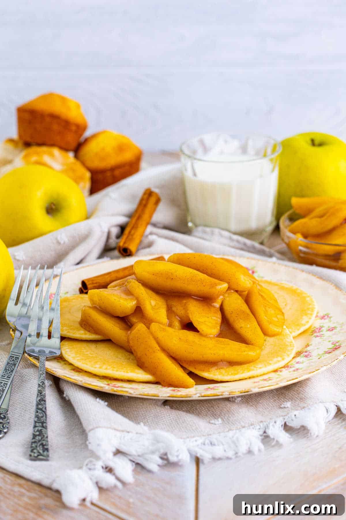 A plate of fluffy pancakes generously topped with warm, spiced fried apples, creating a visually appealing and delicious breakfast or dessert option.