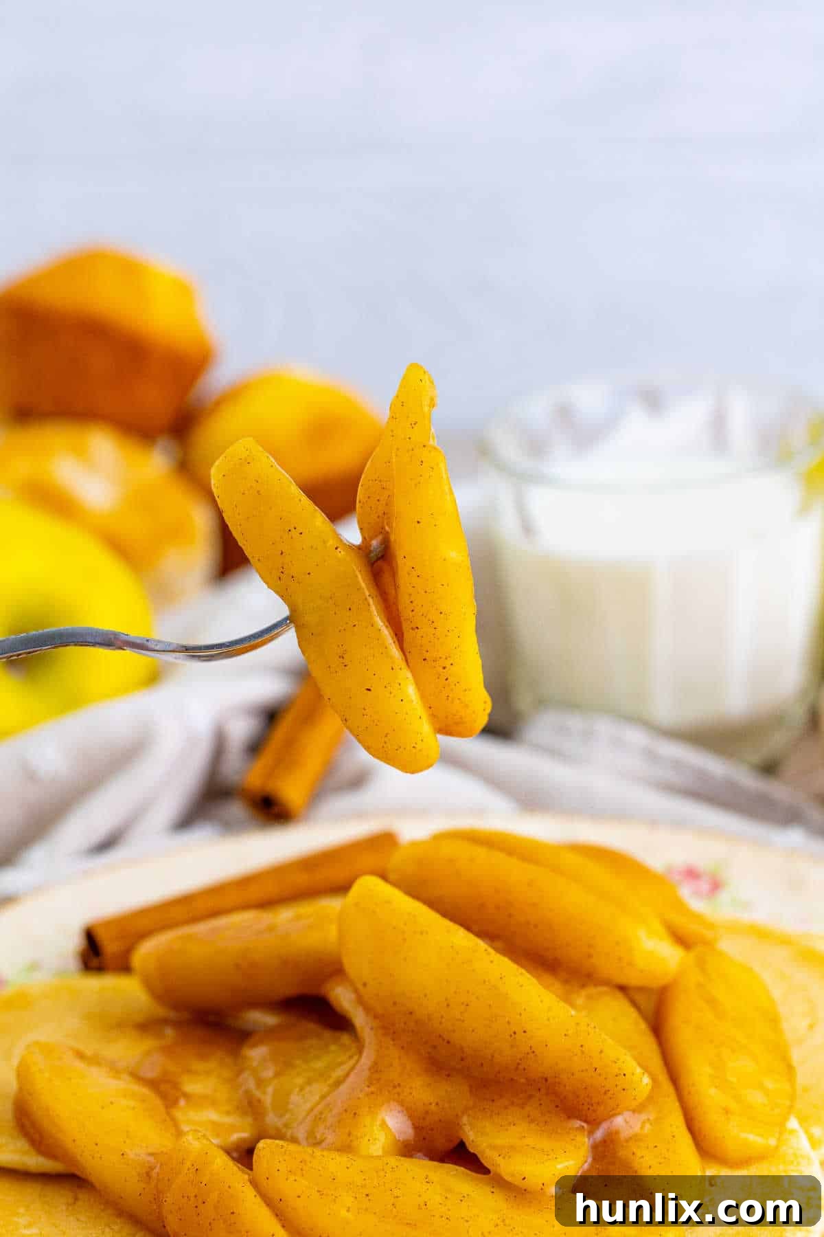 A fork holding a piece of perfectly fried apple, showcasing its tender texture and glossy, spiced coating, inviting a taste.