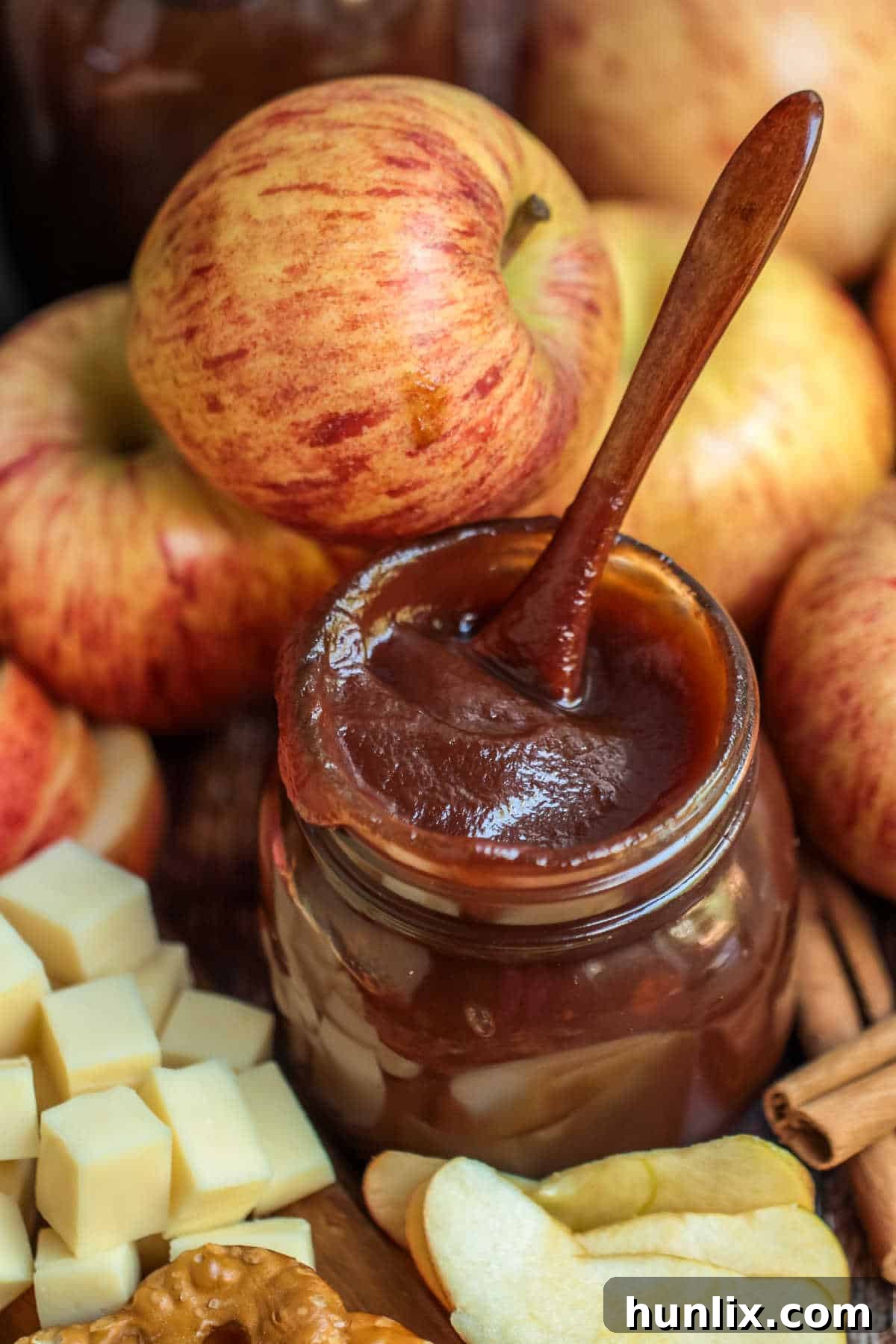 A beautifully sealed jar of Instant Pot Apple Butter, accompanied by a small spoon, showcasing its rich, deep color and smooth texture, set against a rustic background perfect for fall.