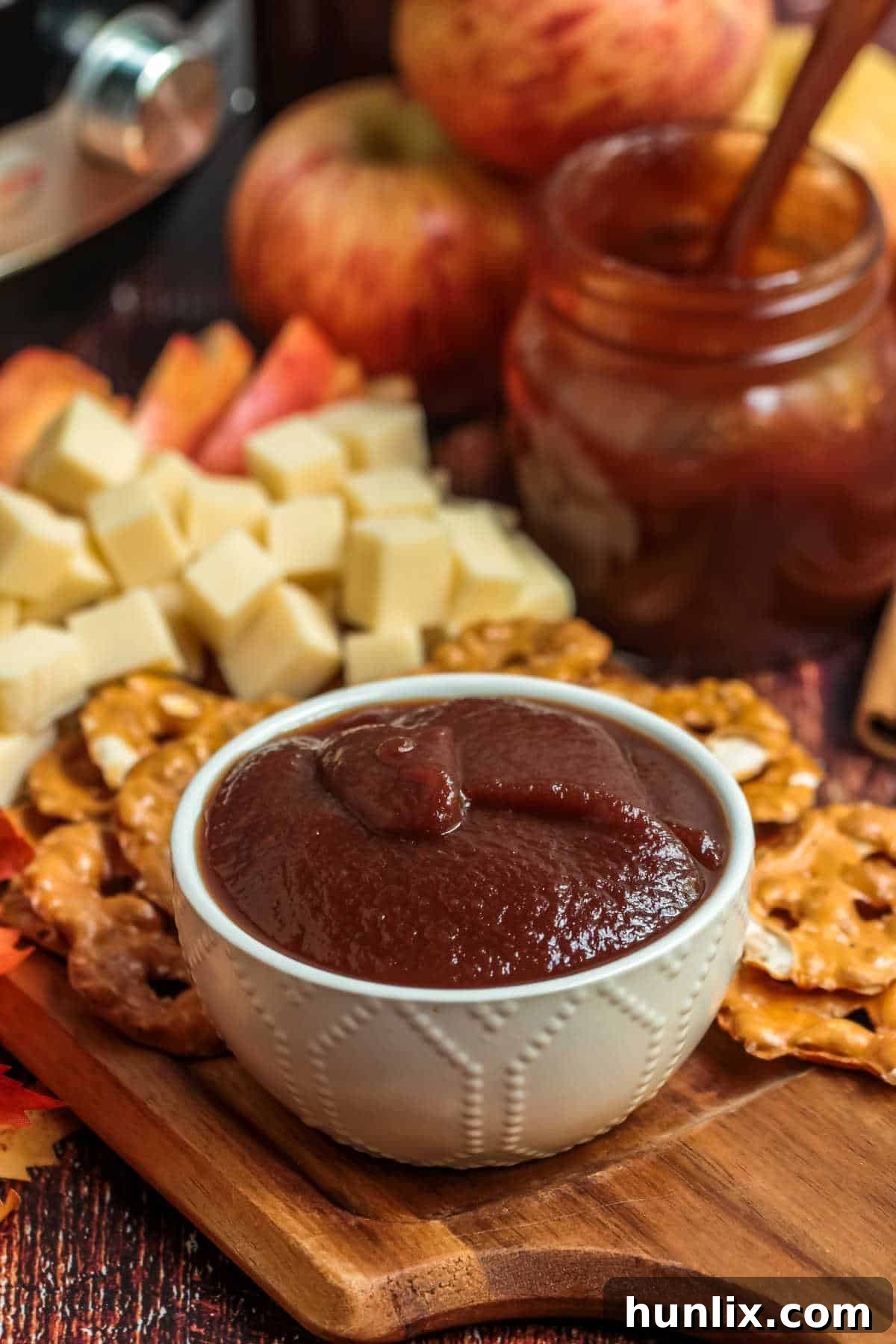A white ceramic bowl filled with glossy, dark Instant Pot Apple Butter, perfectly showcasing its smooth texture and inviting color.