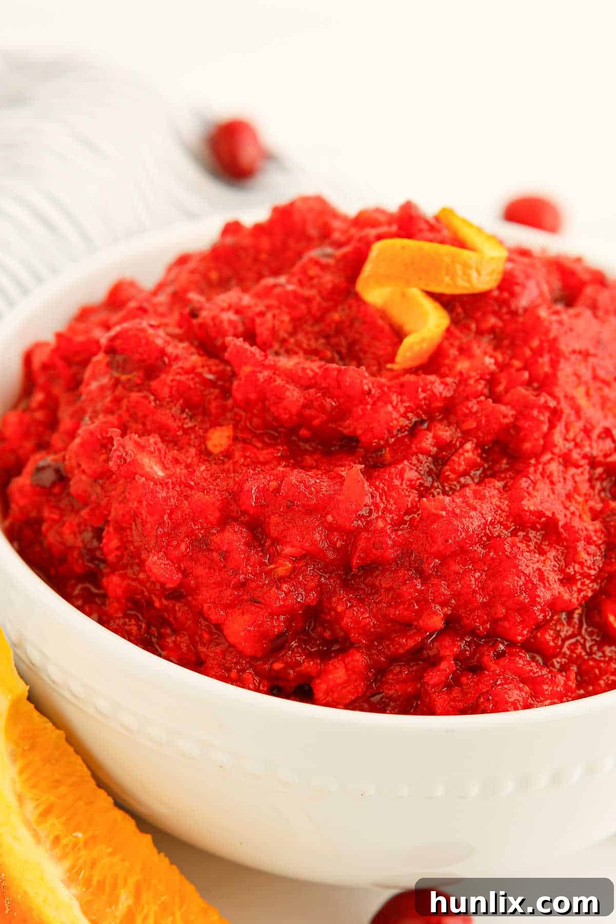 A white serving bowl filled with vibrant cranberry relish, garnished for presentation.