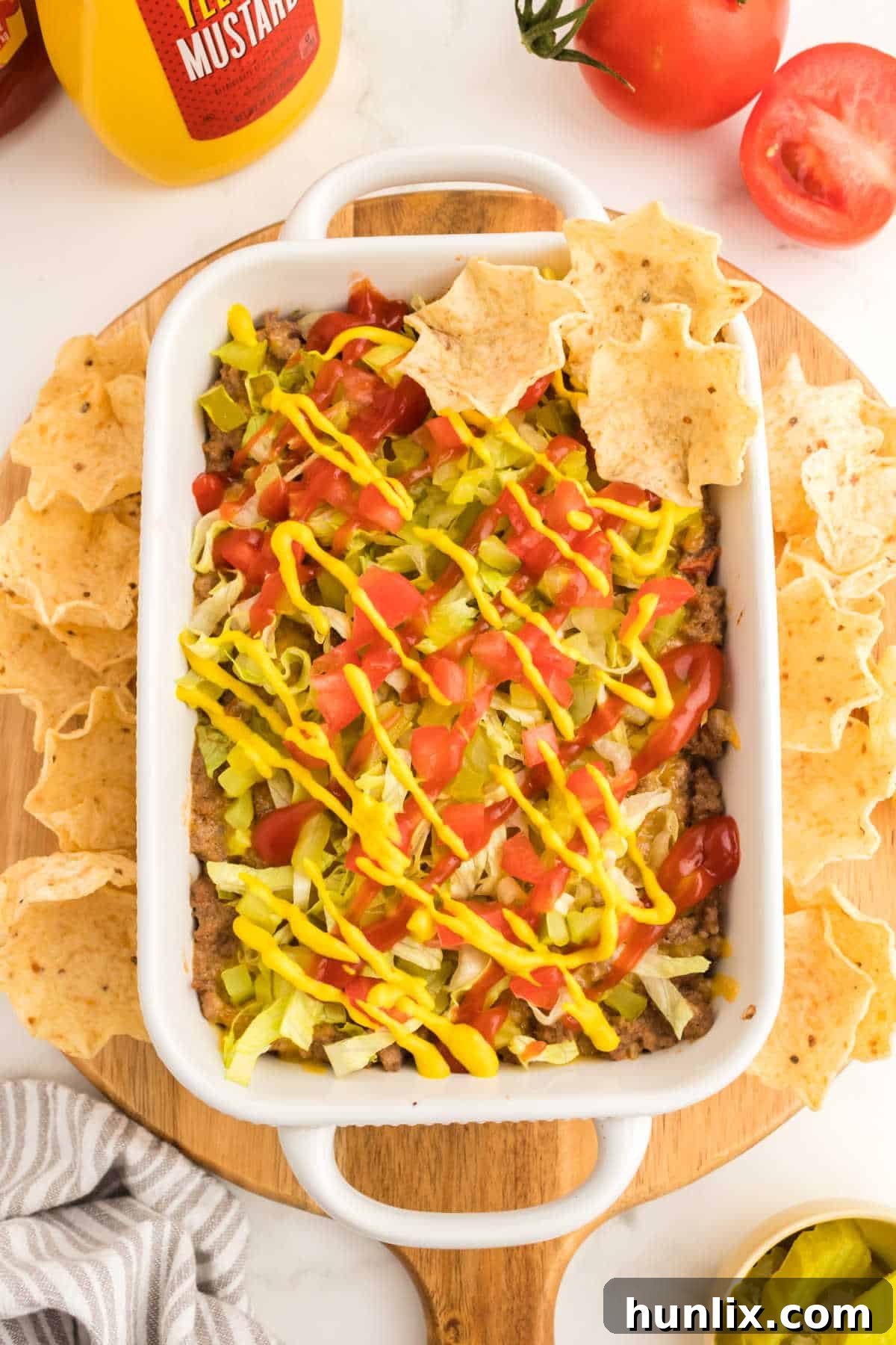 A vibrant baking dish of cheeseburger dip, surrounded by a generous array of crispy tortilla chips, inviting guests to dig in.