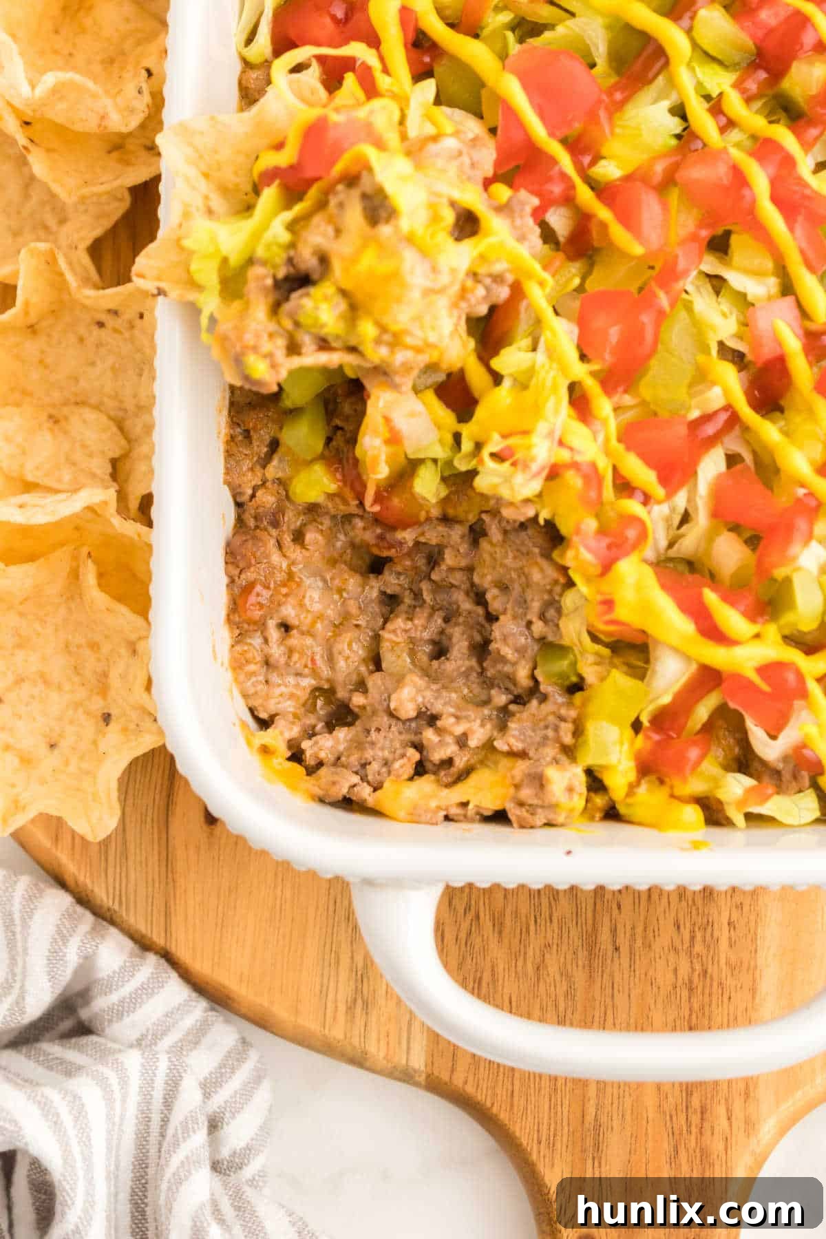 A close-up shot of the rich, bubbly cheeseburger dip resting in a stoneware baking dish, garnished and ready to be enjoyed.