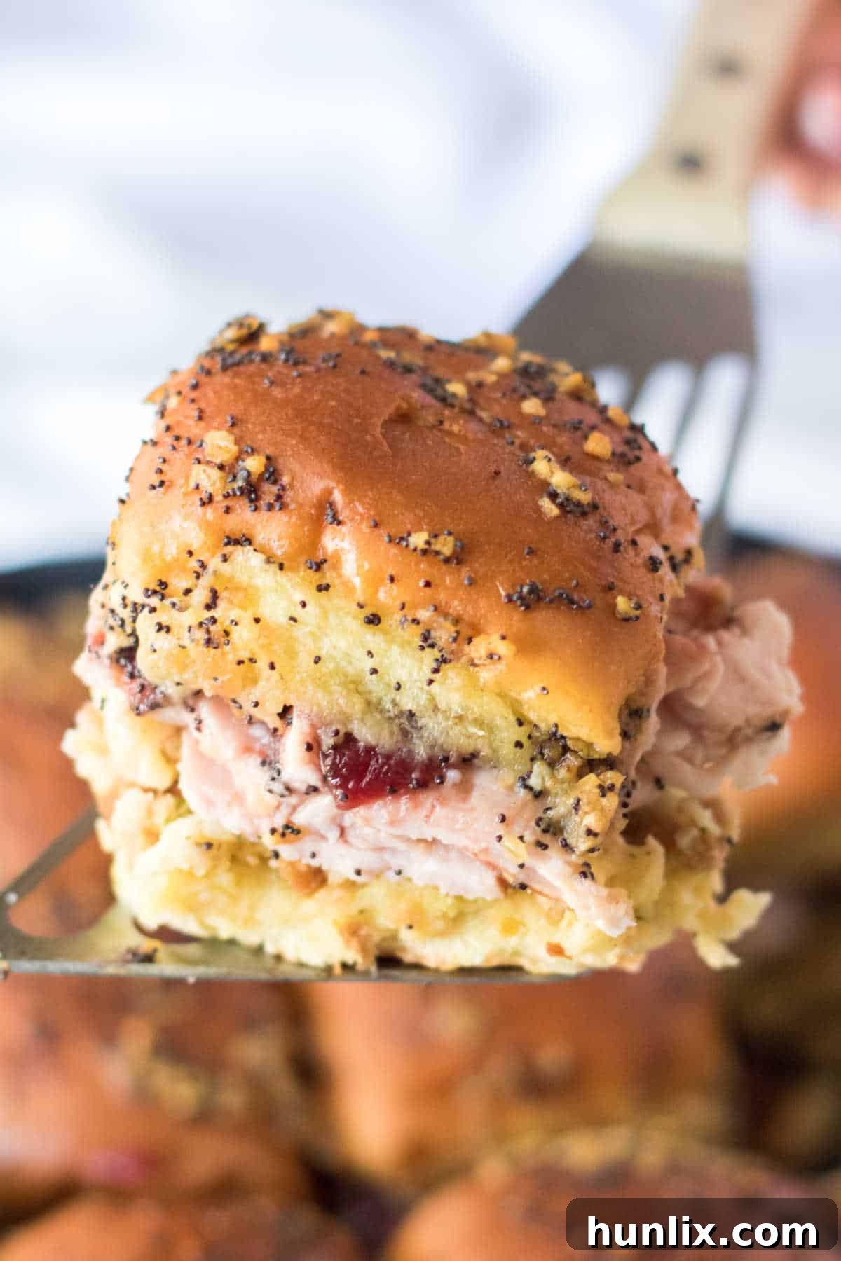 A single Thanksgiving slider lifted on a serving spatula, showcasing its layers.