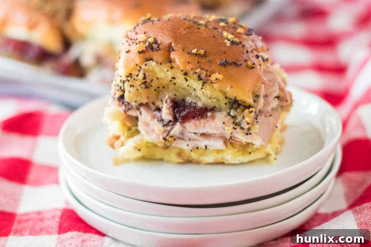 A Thanksgiving turkey slider resting on a stack of white plates.