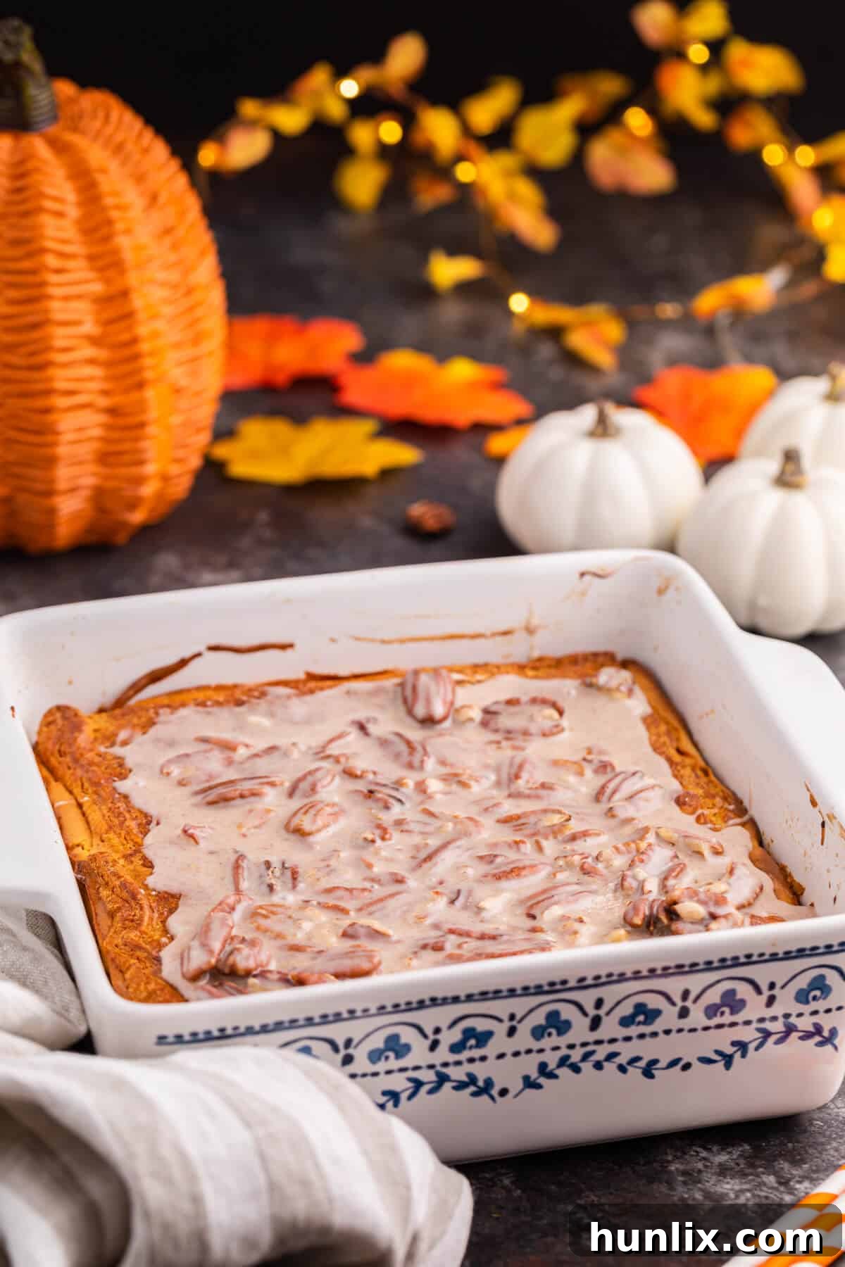 A white pan of pumpkin cream cheese danish bake surrounded by fall decor.