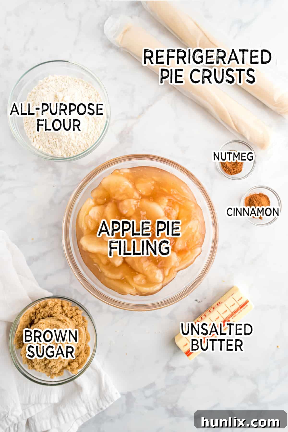 Sheet Pan Apple Pie 3 All the ingredients neatly laid out for preparing apple slab pie, including pie crusts, apple filling, flour, sugar, and spices.