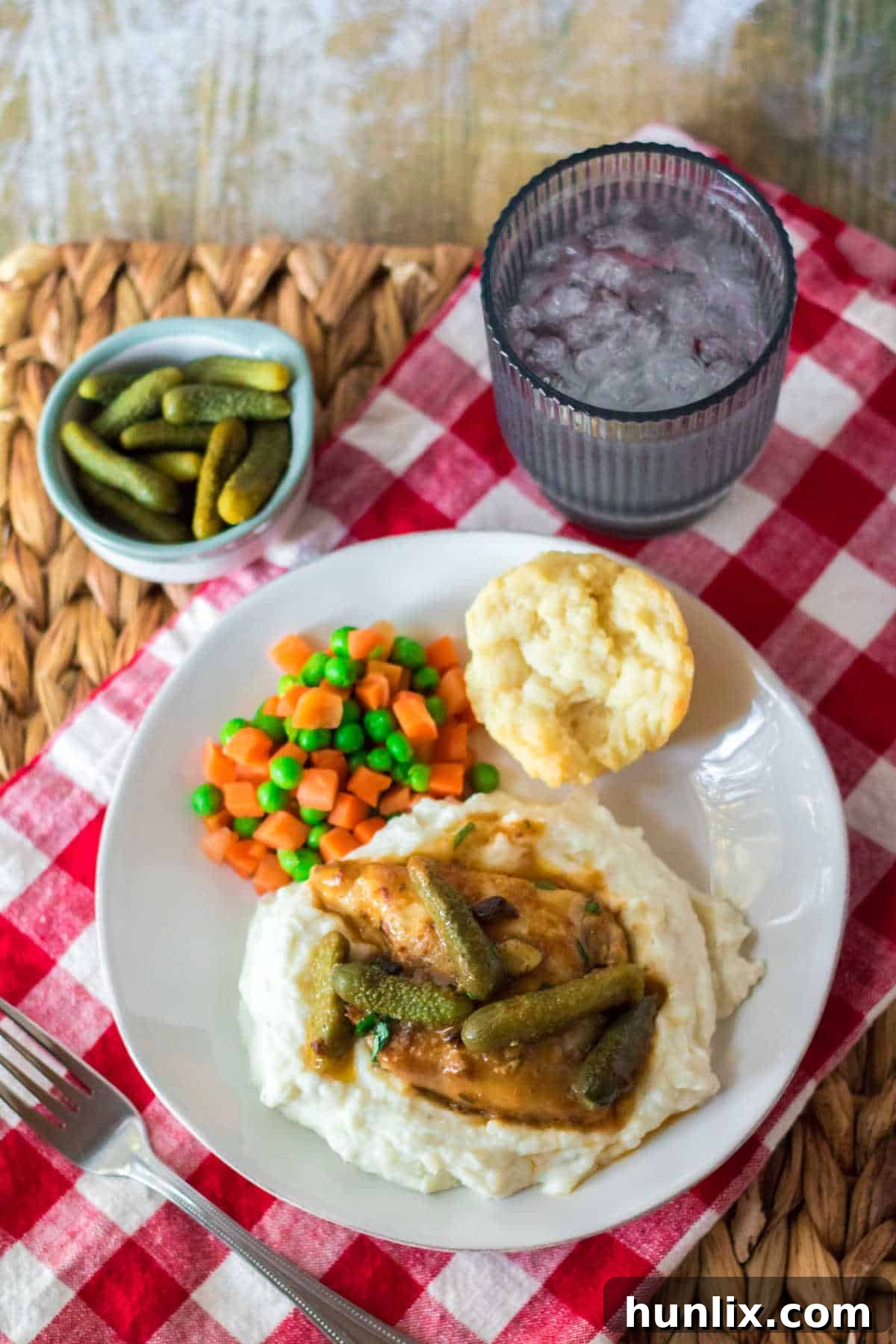 Dill Pickle Slow Cooker Chicken 7 A plate with pickle chicken, mashed potatoes, peas, carrots and a bun.
