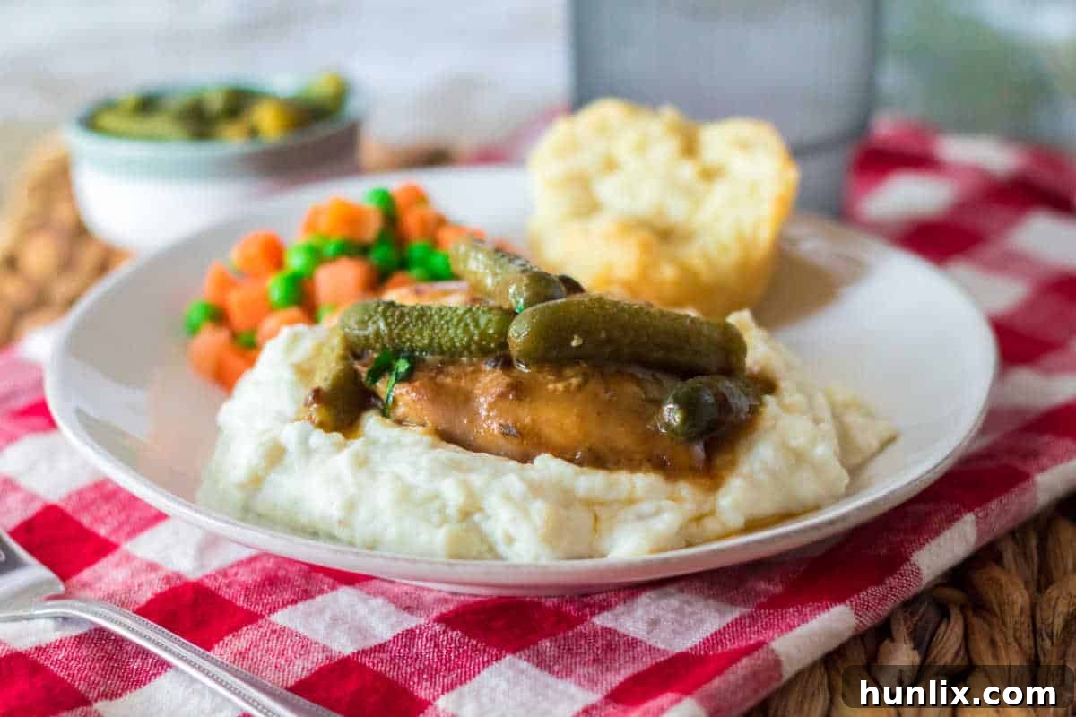 Dill Pickle Slow Cooker Chicken 8 Pickle chicken served on plate with mashed potatoes, veggies and a bun.