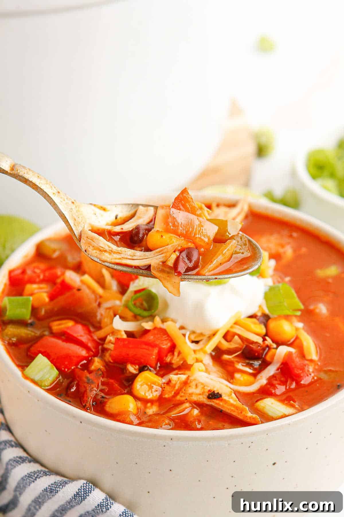 A spoonful of chicken fajita soup held over a full bowl, showcasing the rich texture and ingredients.