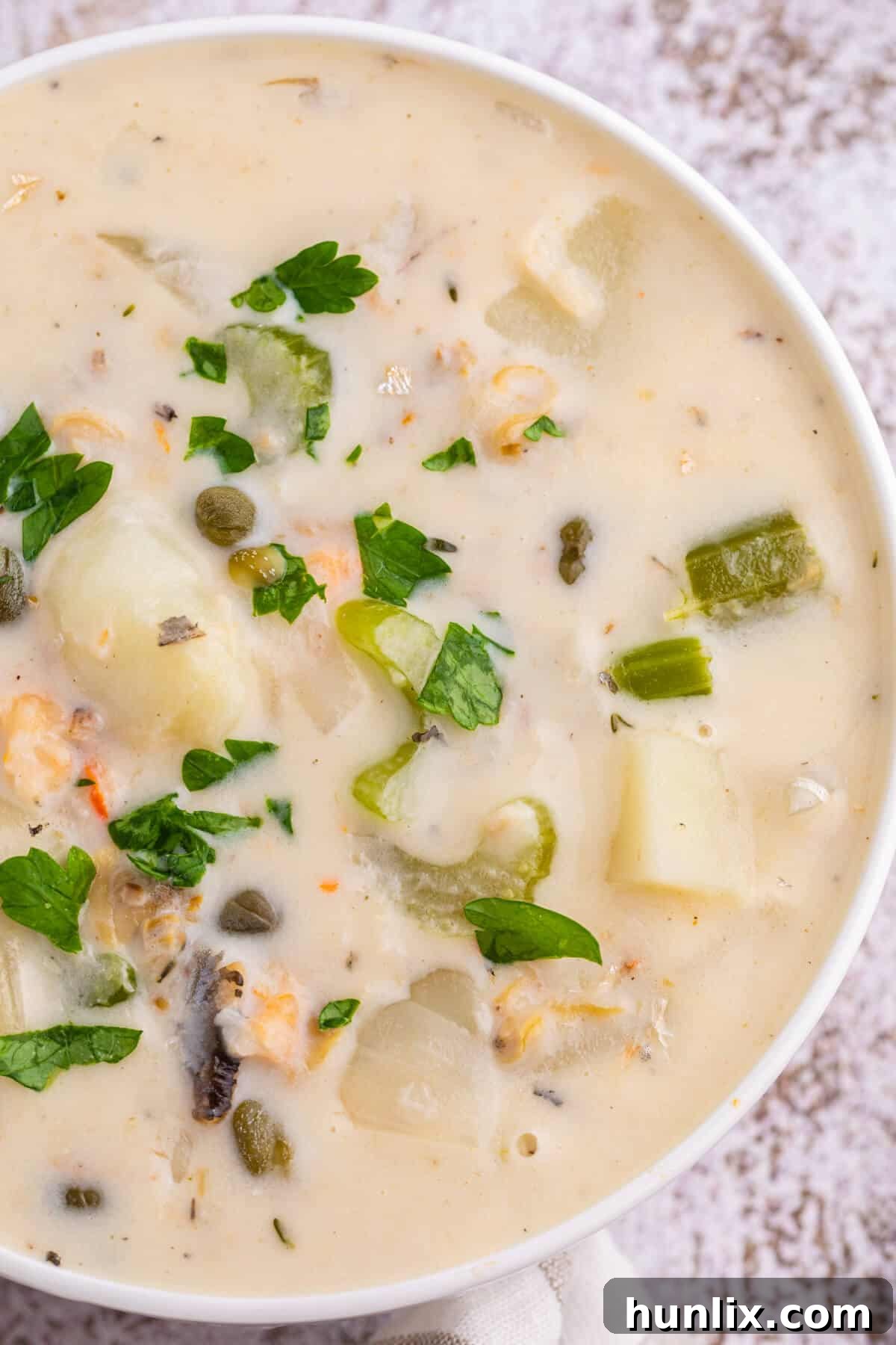 Coastal Comfort Chowder 5 A pristine white bowl of seafood chowder, artfully arranged to highlight the creamy texture and fresh ingredients, ready to be enjoyed.