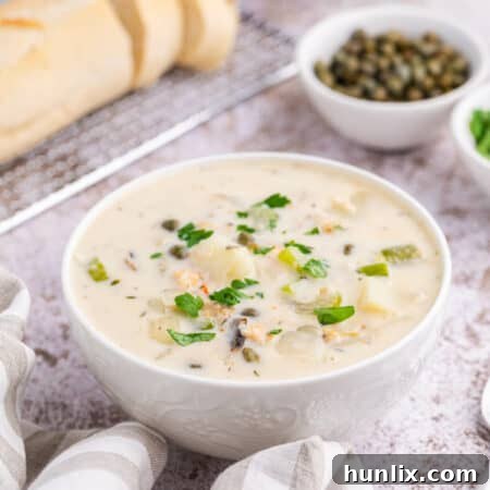 A pristine white bowl filled with creamy seafood chowder, garnished with fresh parsley.
