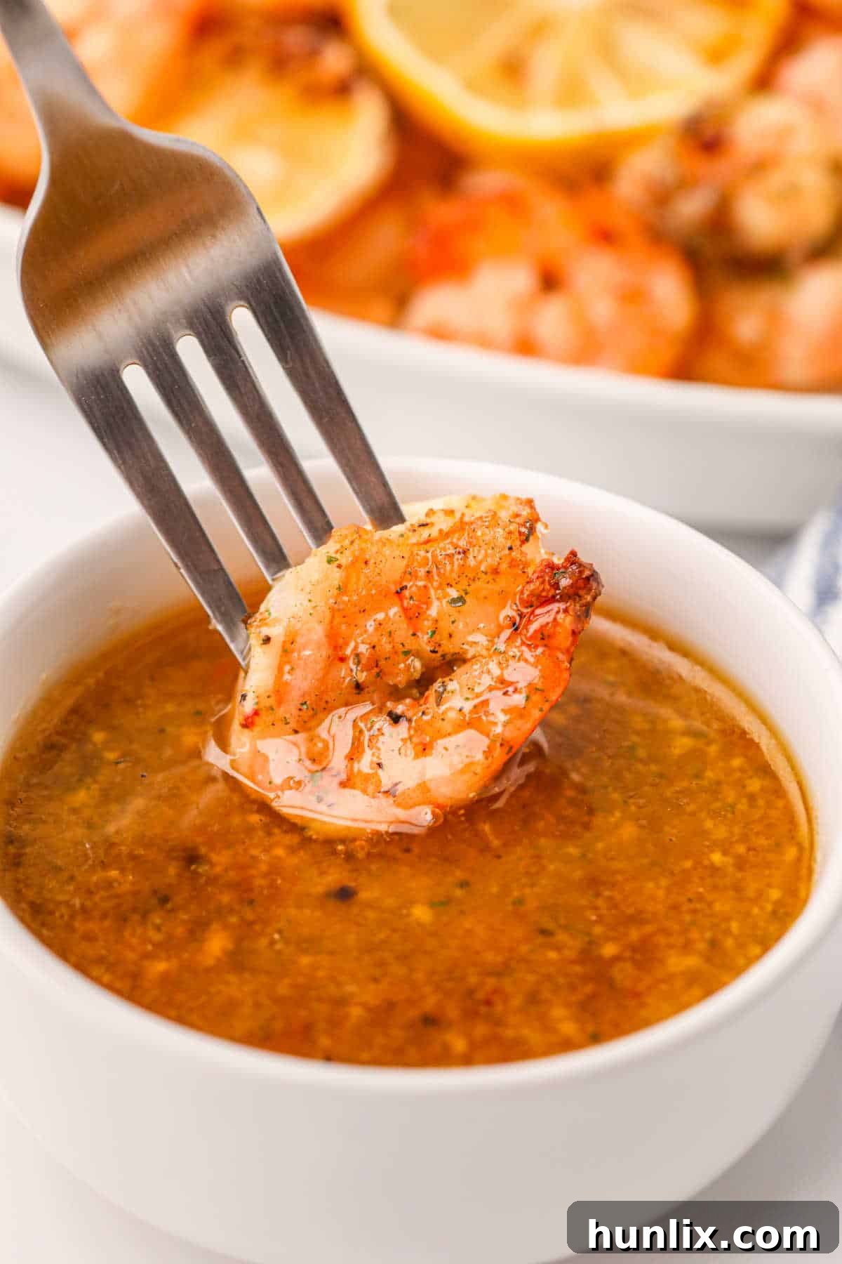 Crispy Air Fryer Shrimp 8 A fork holding a piece of air fryer shrimp, dipping it into a small bowl of sauce.