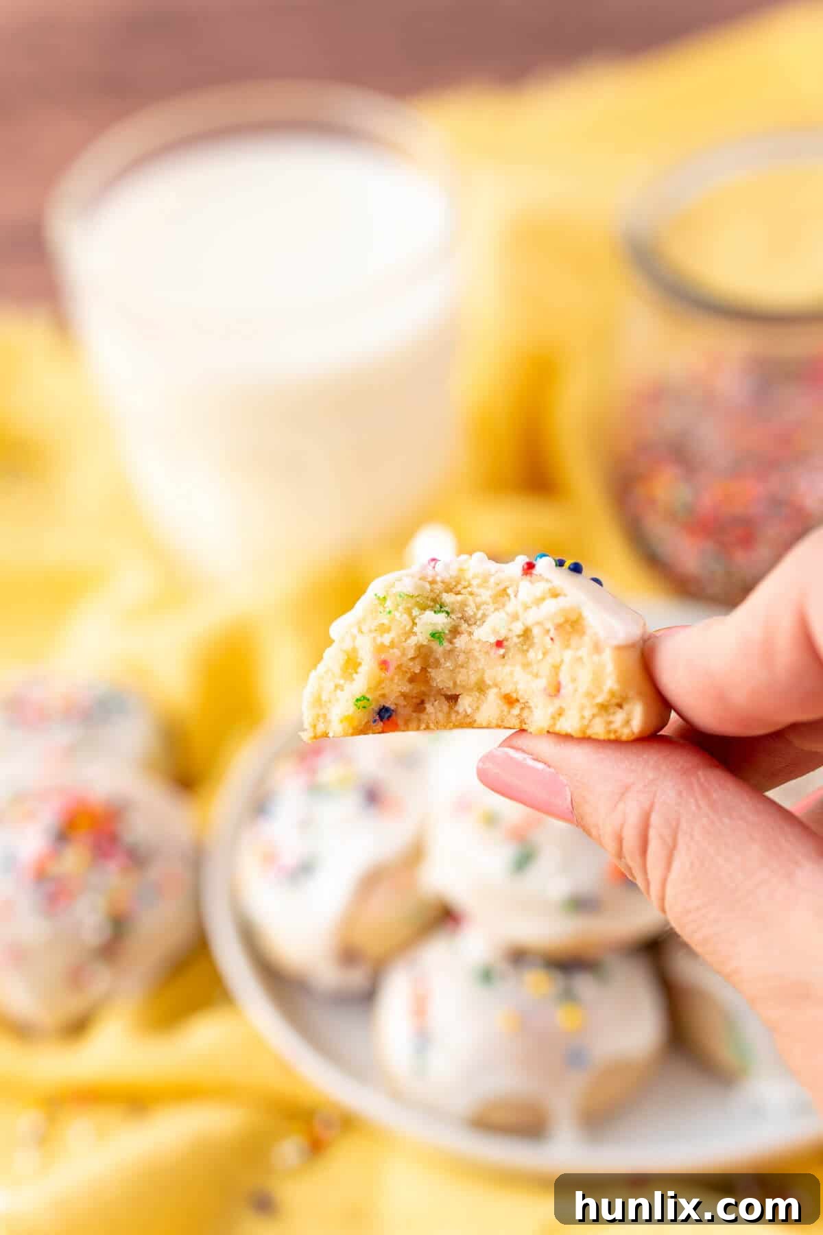 A hand holds a sweetened condensed milk cookie with a bite taken out, revealing its soft interior and perfect crumb.