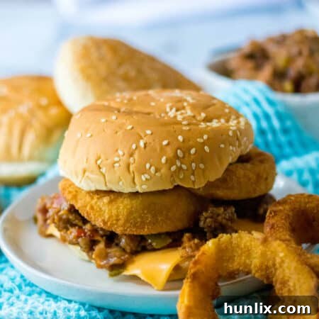 A rodeo sloppy joe on a plate with onion rings.