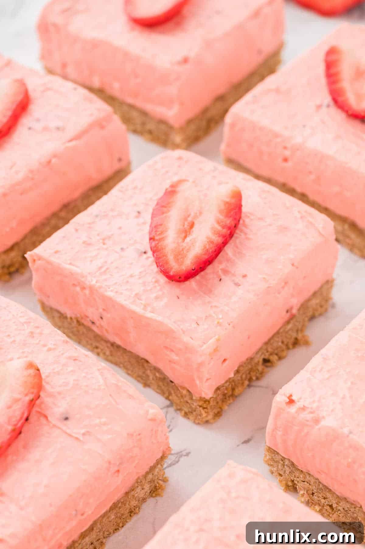 Strawberry cheesecake bars cut into squares, showcasing creamy filling and a golden crust.