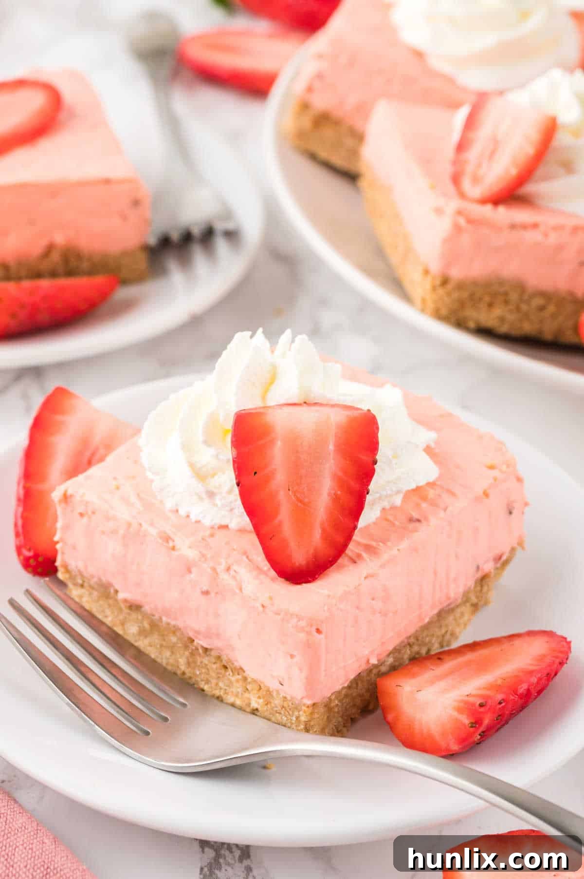 A Strawberry Cheesecake Bar on a plate with a fork, ready to be eaten.