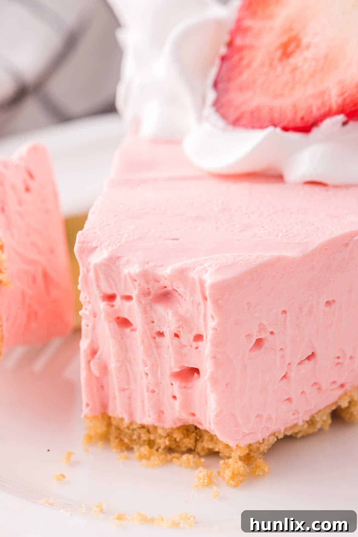 Neon Nectar Pie 10 A slice of vibrant pink Kool-Aid pie on a white plate, with a small bite taken from the end, showing the creamy texture and inviting taste.