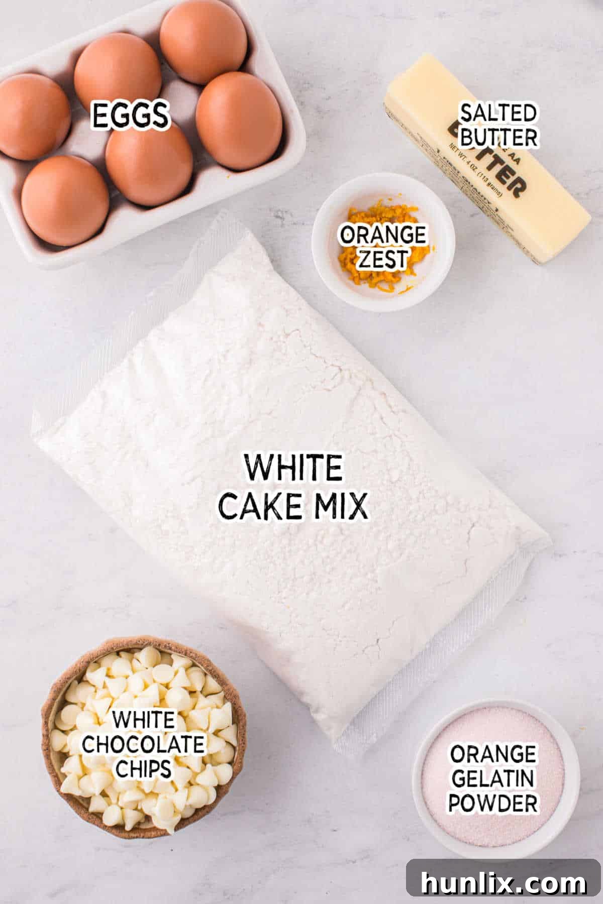 A collection of ingredients for orange creamsicle cookies laid out on a clean white surface.