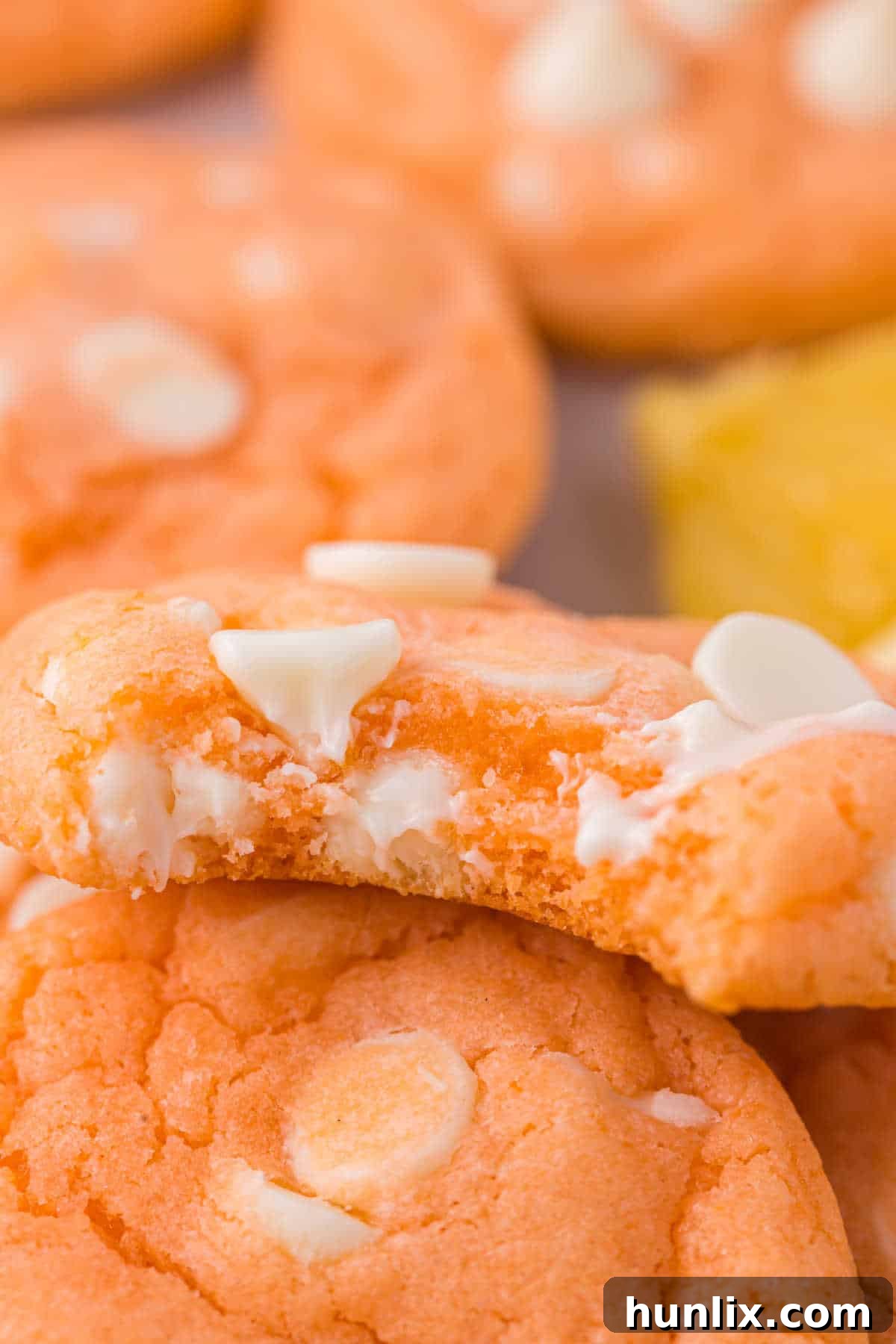 An orange creamsicle cookie with a bite taken out, revealing its soft and chewy texture.