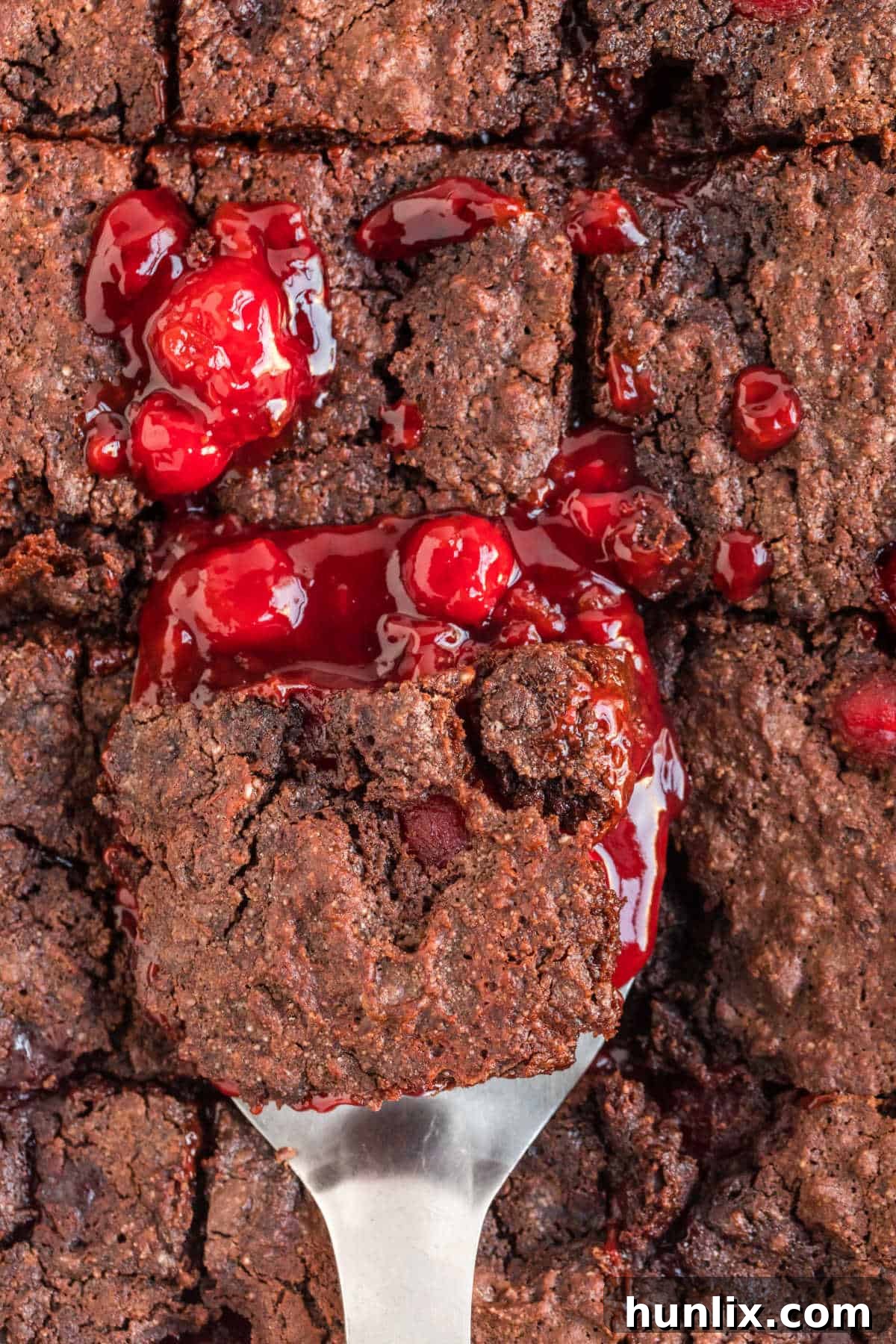 A spatula with a slice of black forest dump cake over a pan.