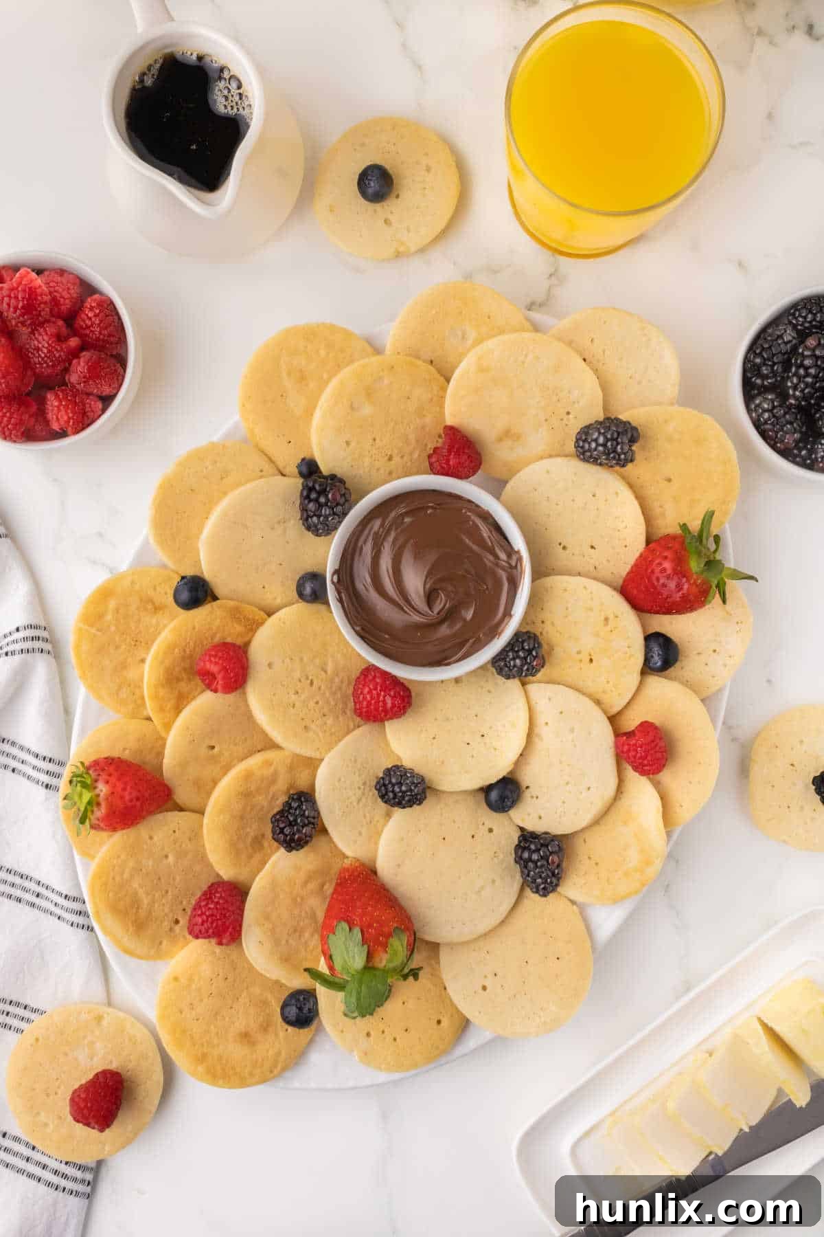 A platter of mini pancakes with fresh berries.