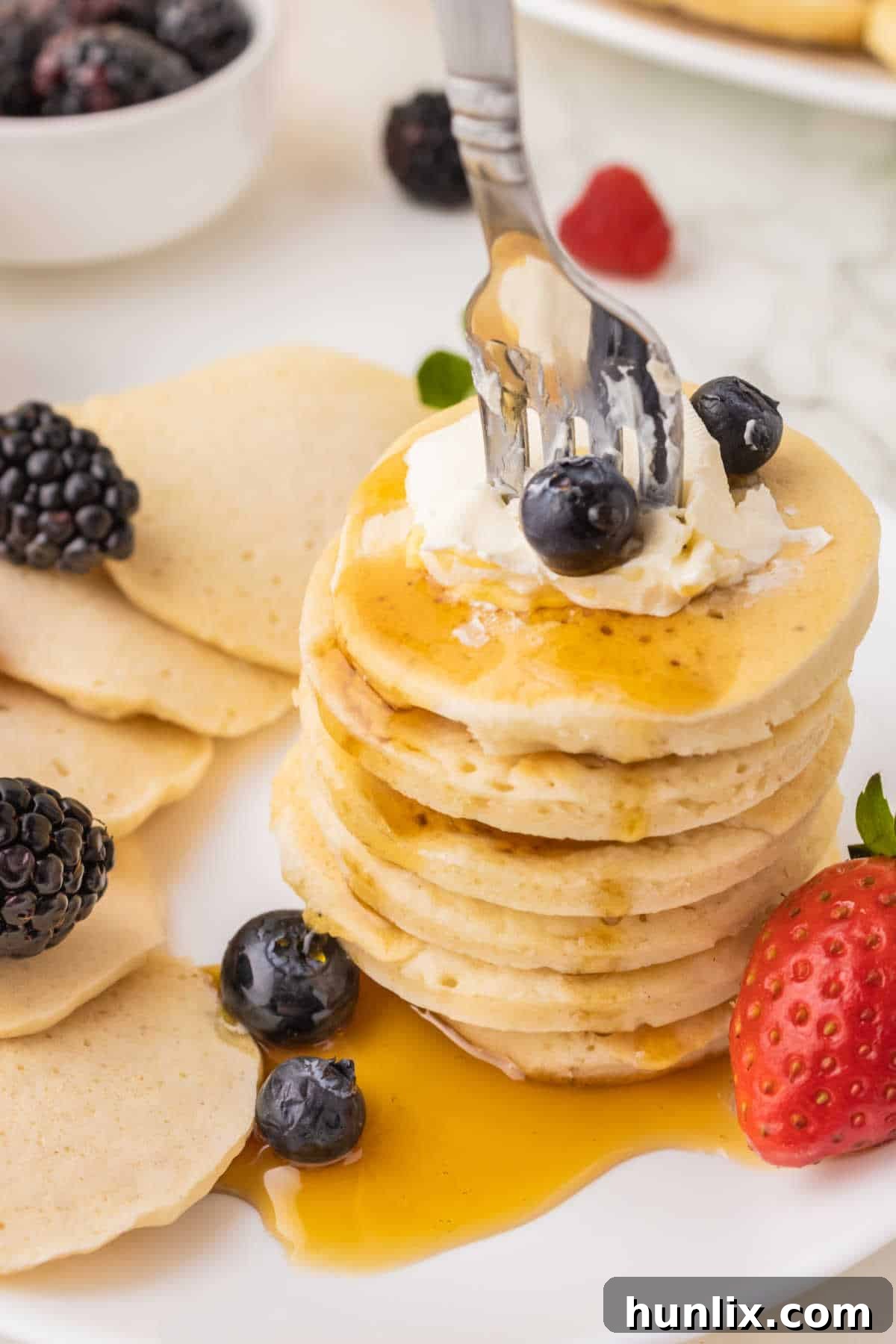 A stack of mini pancakes with a fork in them.