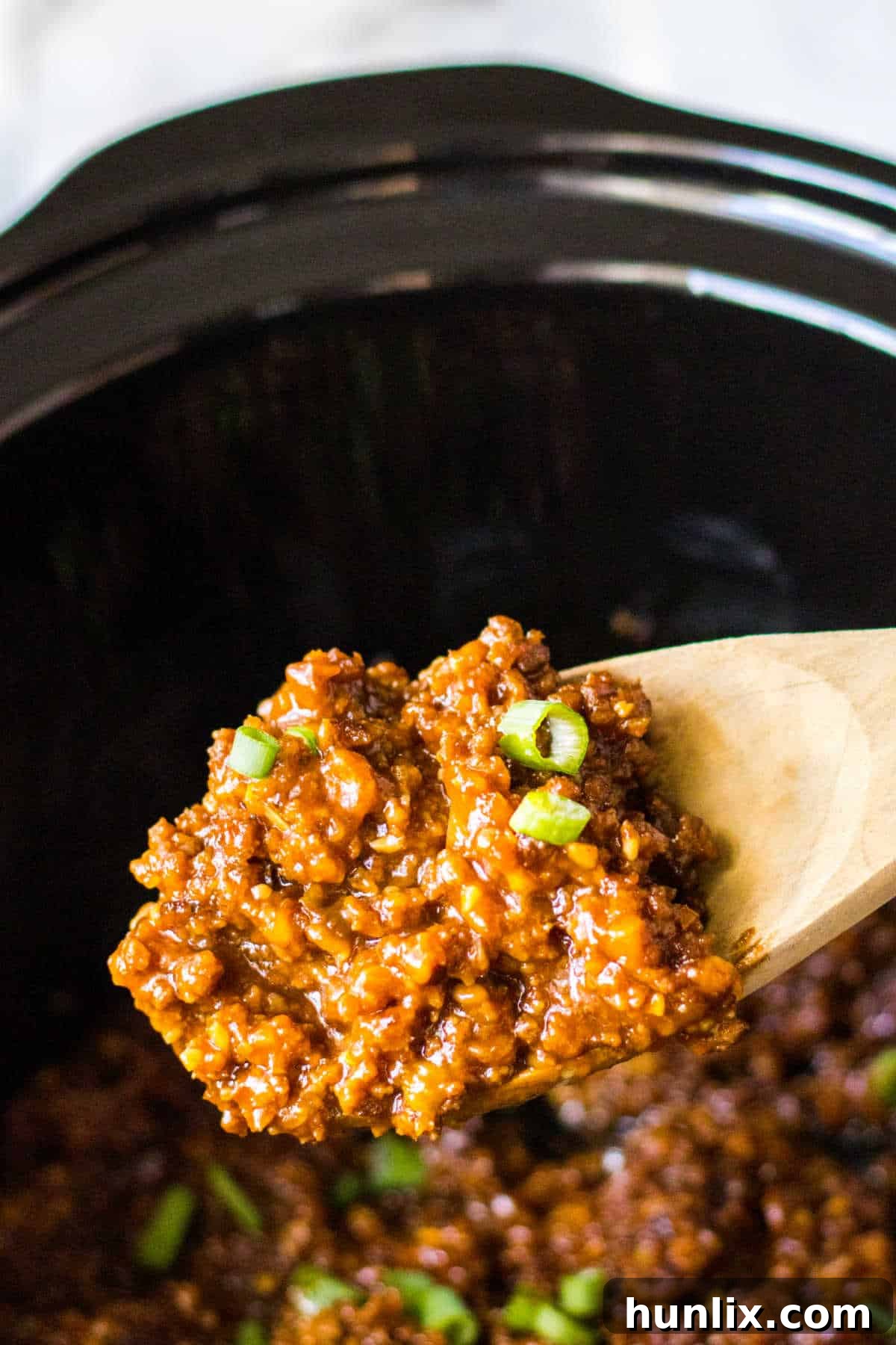 A scoop of Korean sloppy joe meat on a wooden serving spoon, highlighting its saucy texture.