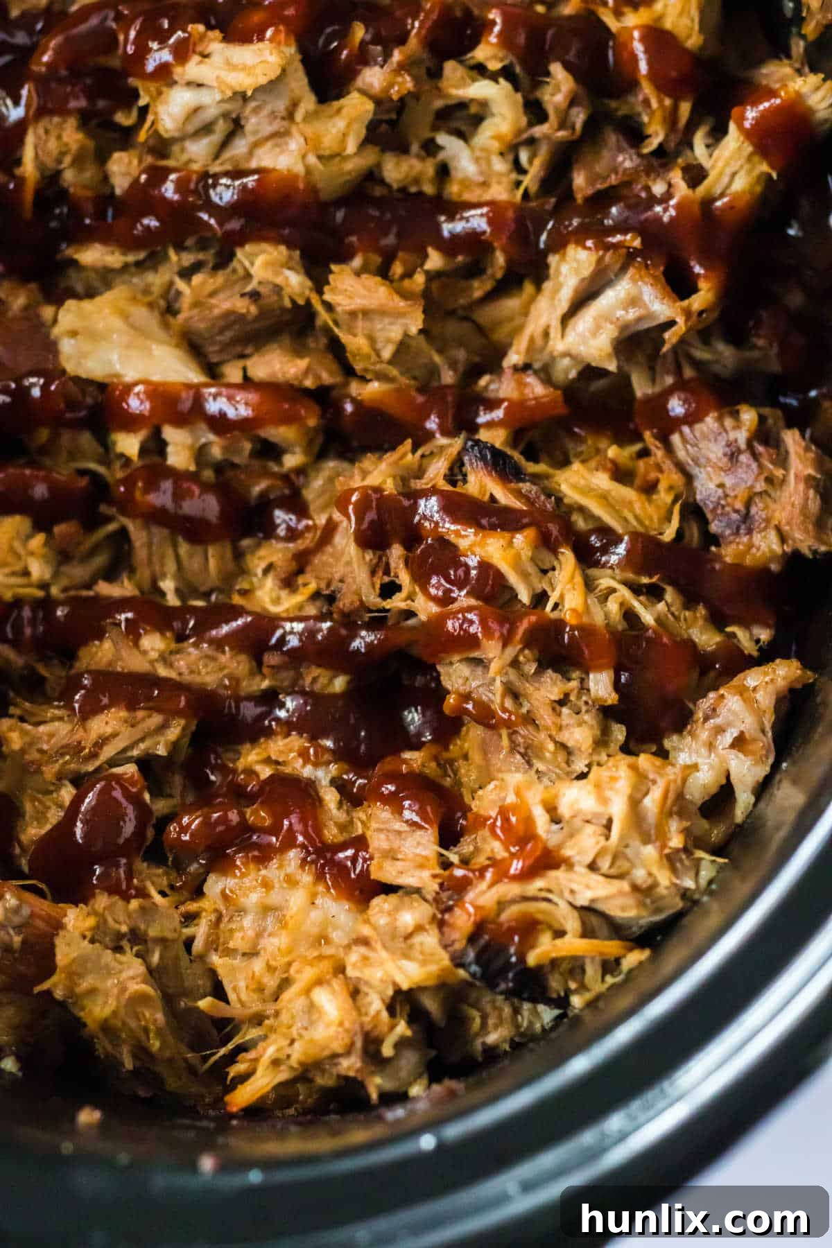 Close up of root beer pulled pork in a slow cooker, showcasing its rich, deep color and inviting texture.