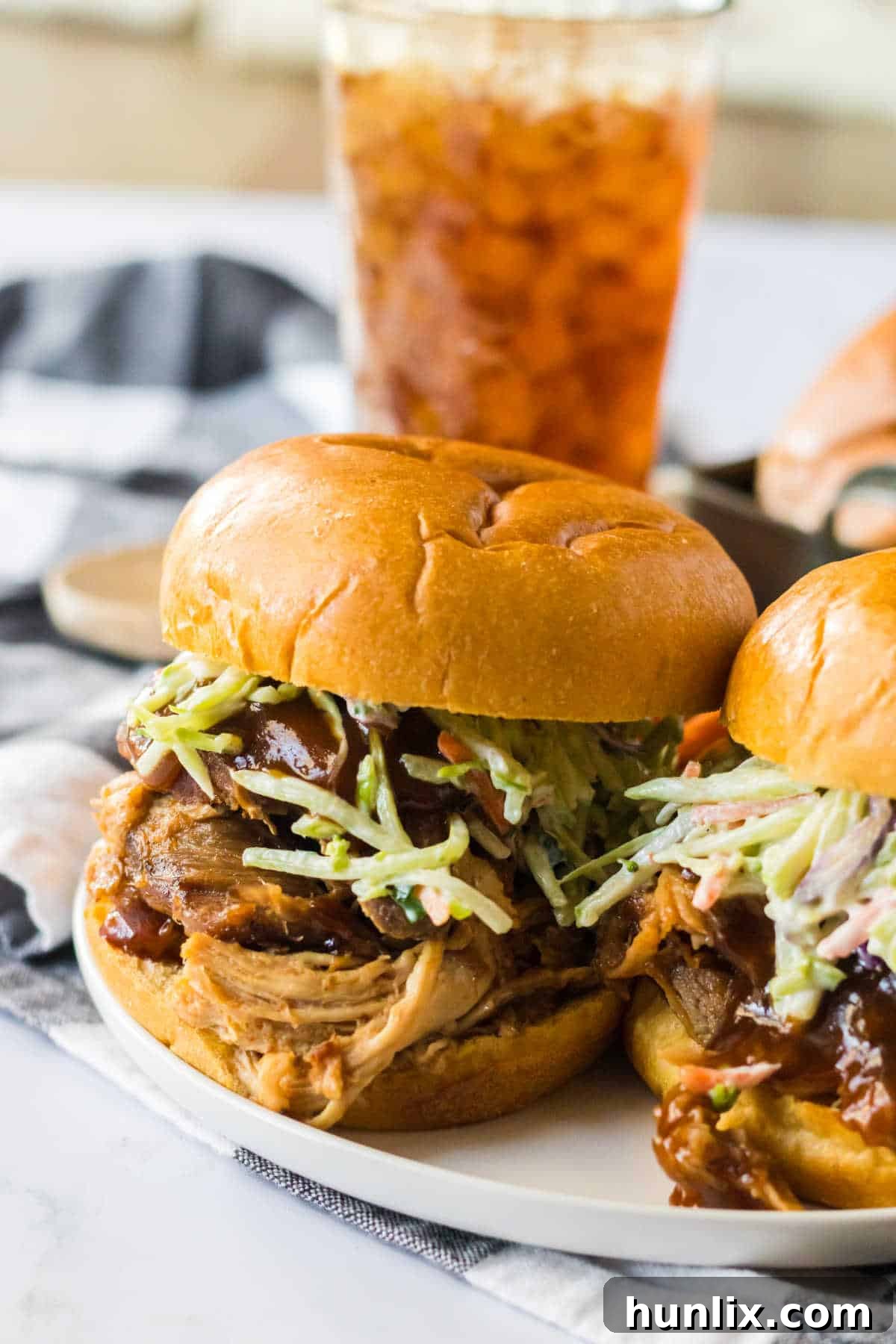 Two generous servings of root beer pulled pork sandwiches topped with coleslaw on soft buns, ready to be enjoyed.