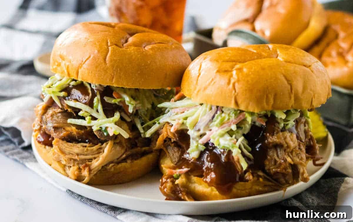 Two perfectly prepared root beer pulled pork sandwiches with coleslaw on a plate, ready to be enjoyed.