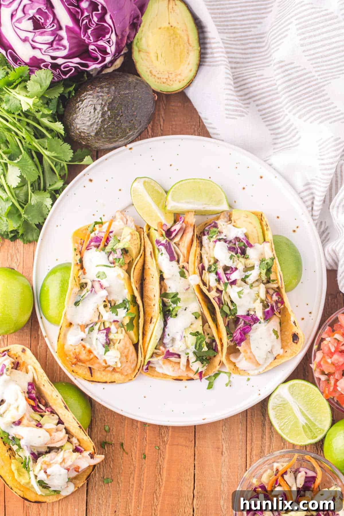 Freshly prepared fish tacos arranged beautifully on a white plate, garnished with lime wedges and cilantro.