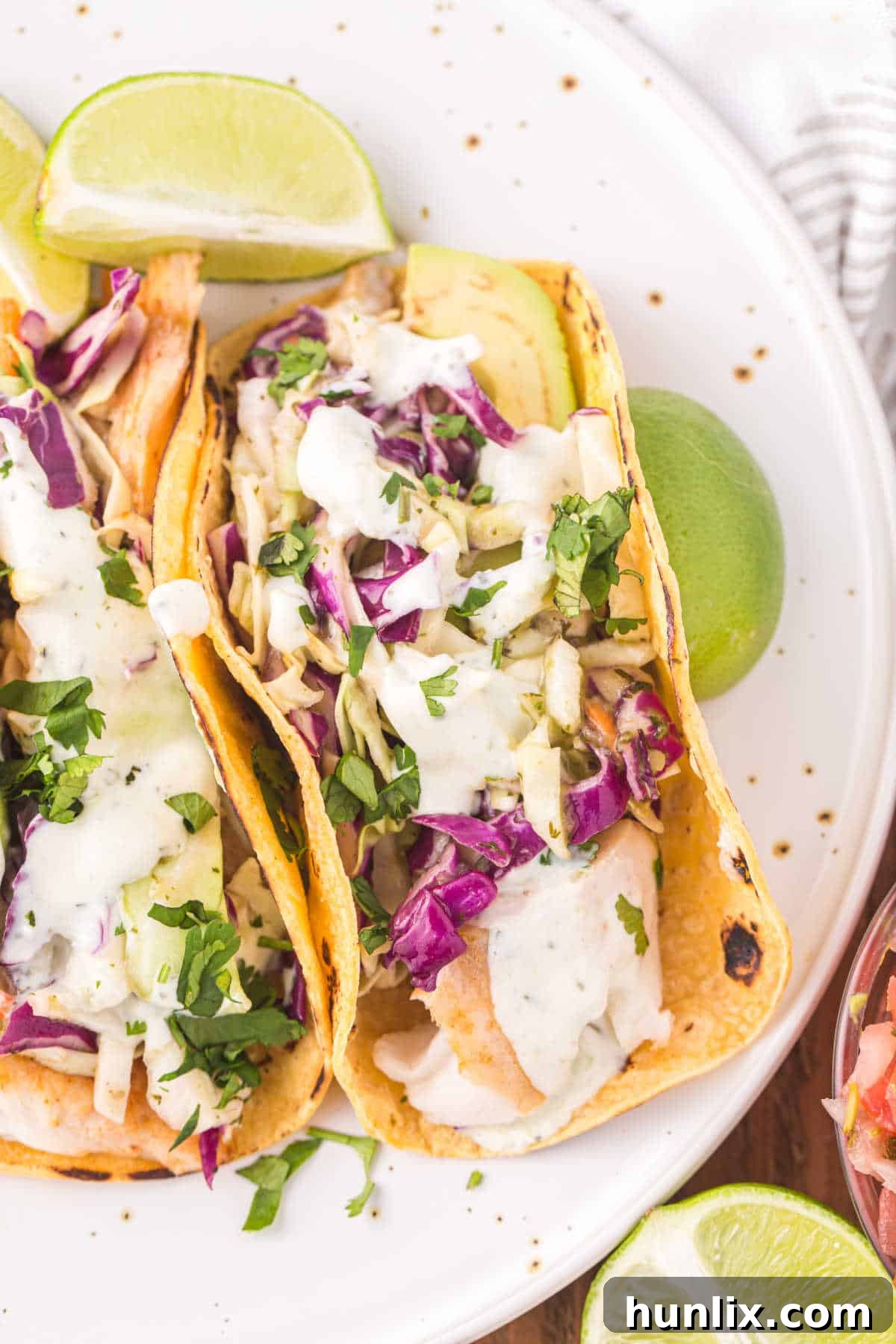 Two hands holding a fish taco, showing the delicious filling and creamy sauce.