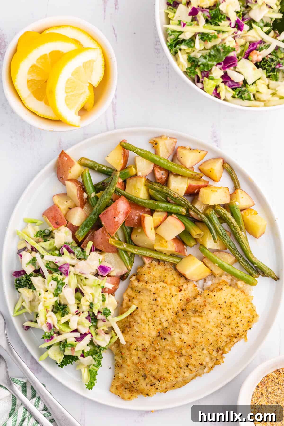 A perfectly cooked High Liner Lemon Pepper Sole fillet served on a white plate with beautifully roasted potatoes and green beans, garnished with a fresh lemon wedge.