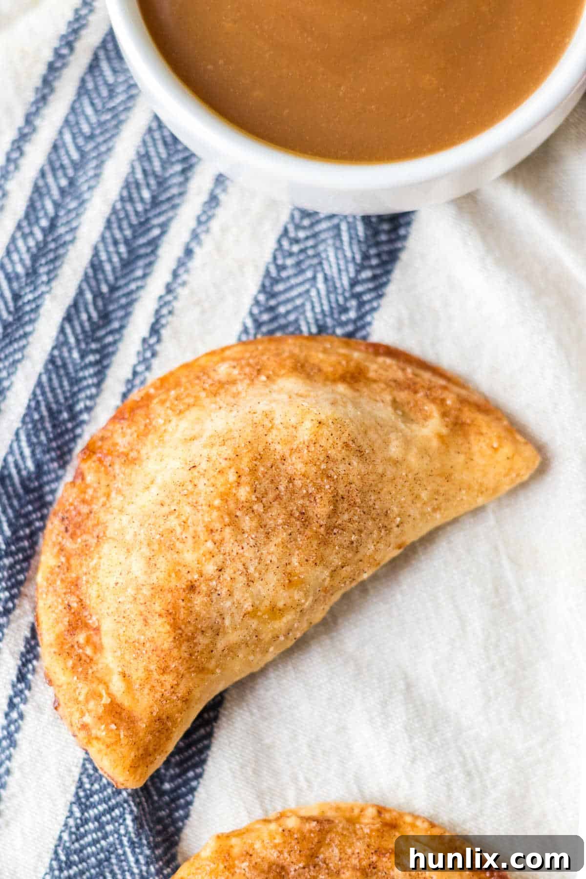 The golden-brown air fryer caramel apple empanadas resting on a rustic linen cloth.